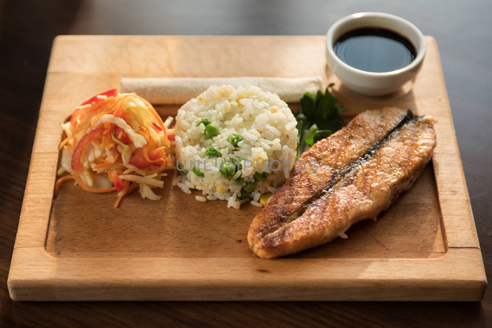 Grilled salmon with rice and vegetables at wooden table