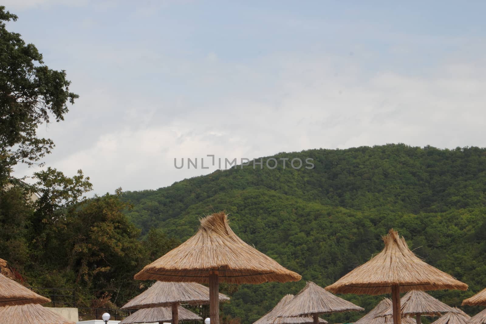 Straw umbrellas on the beach in Russia on a background of mountains