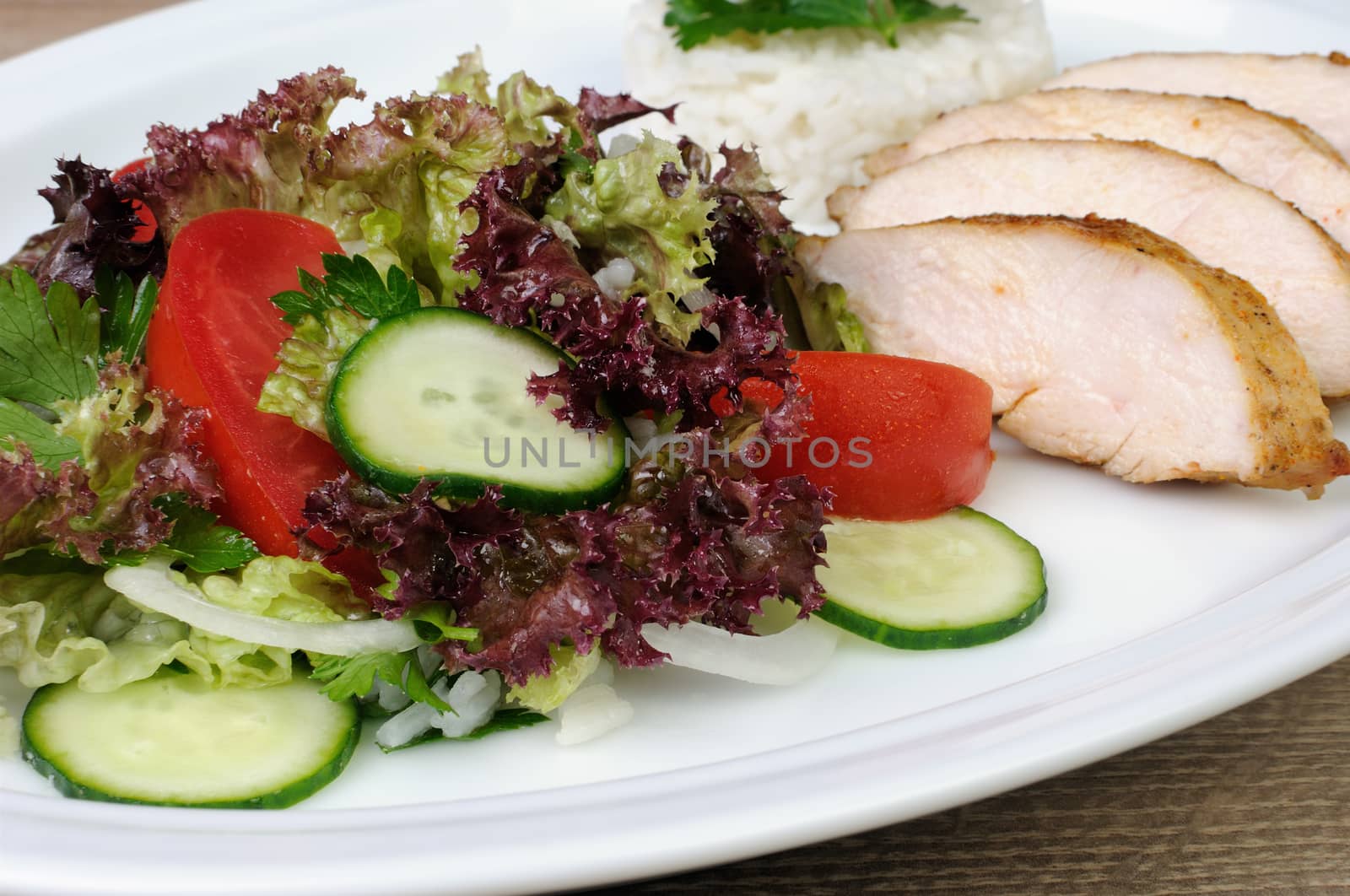 salad of lettuce, cucumber and tomato with slices of chicken breast