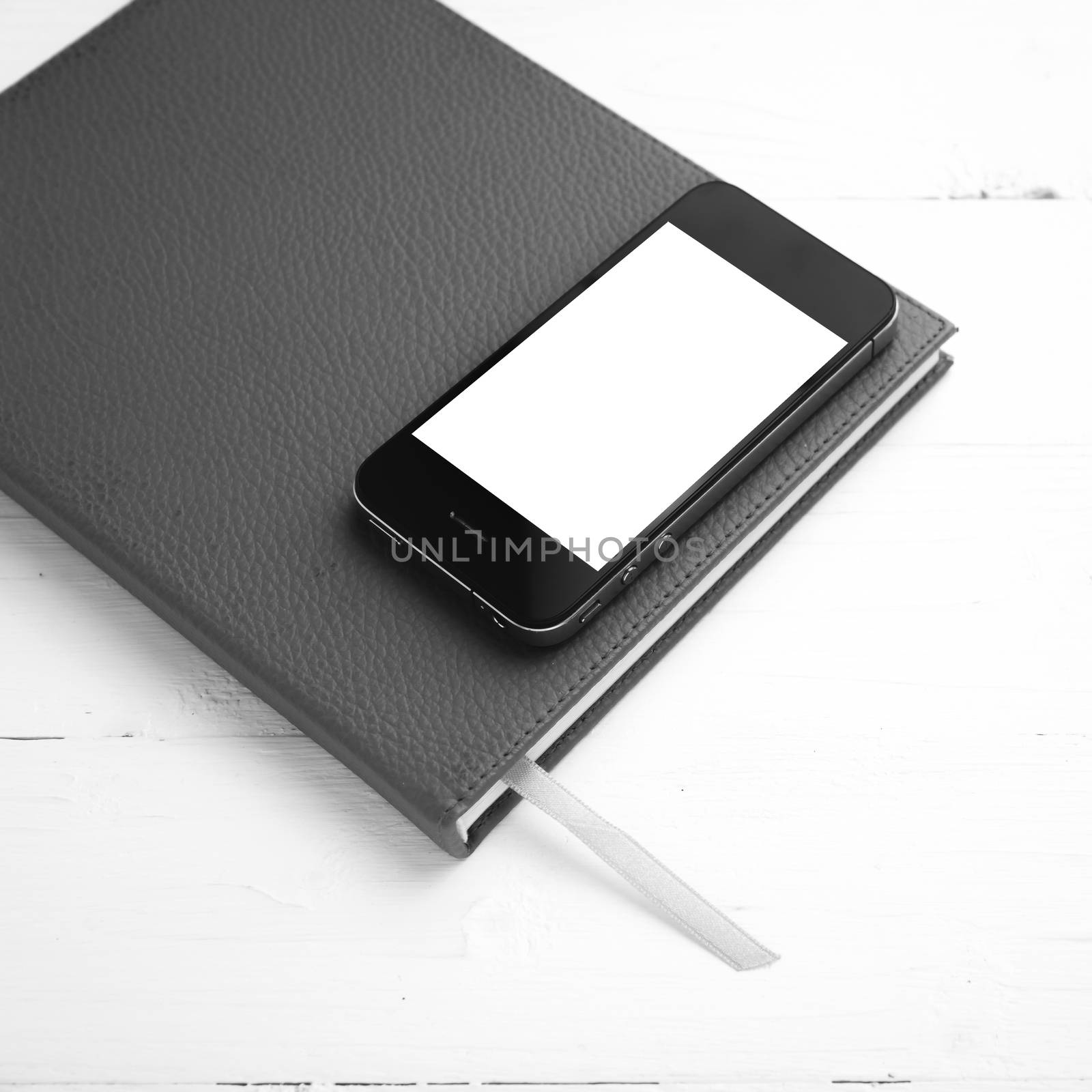 cellphone on notebook over white table black and white tone color style