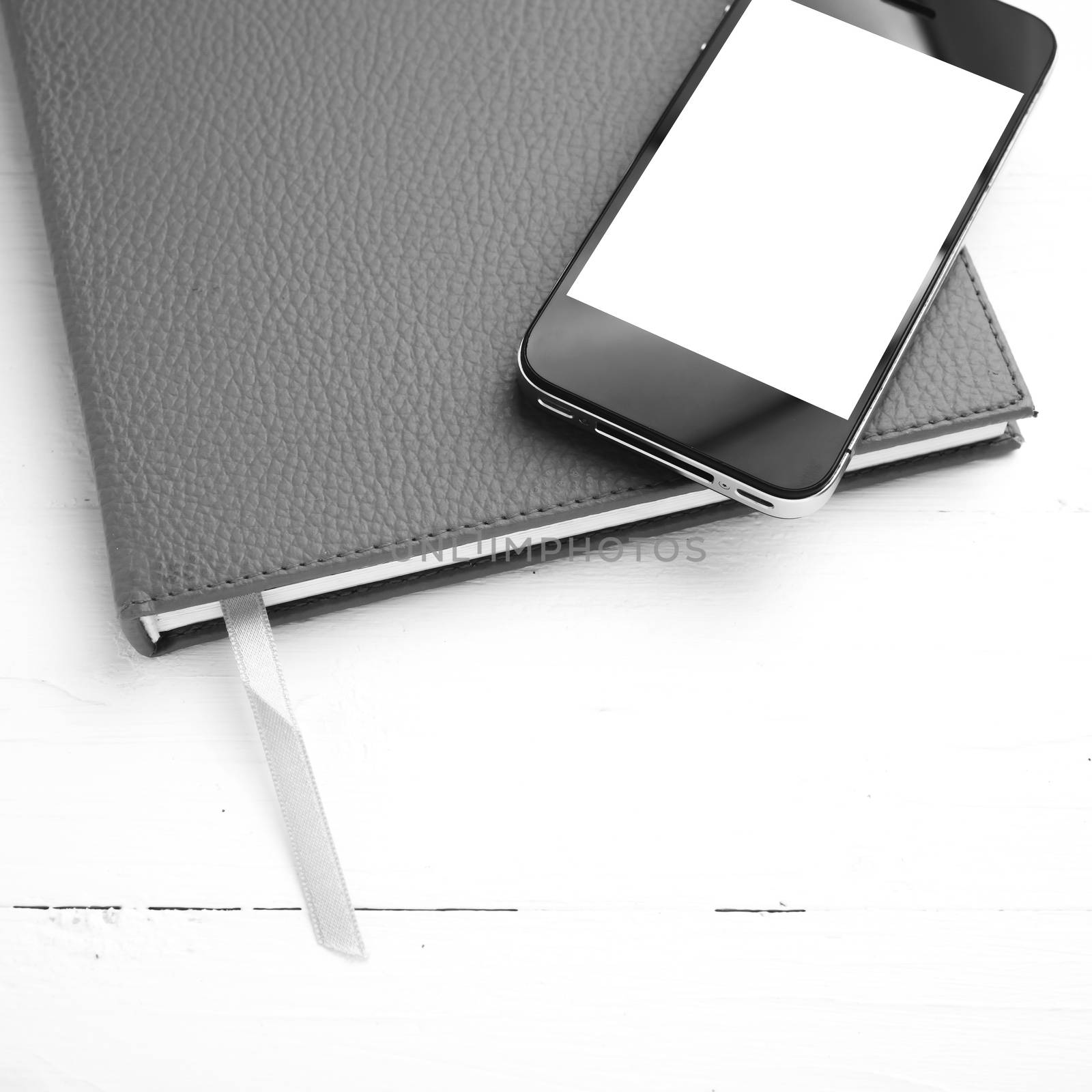 cellphone on notebook over white table black and white tone color style