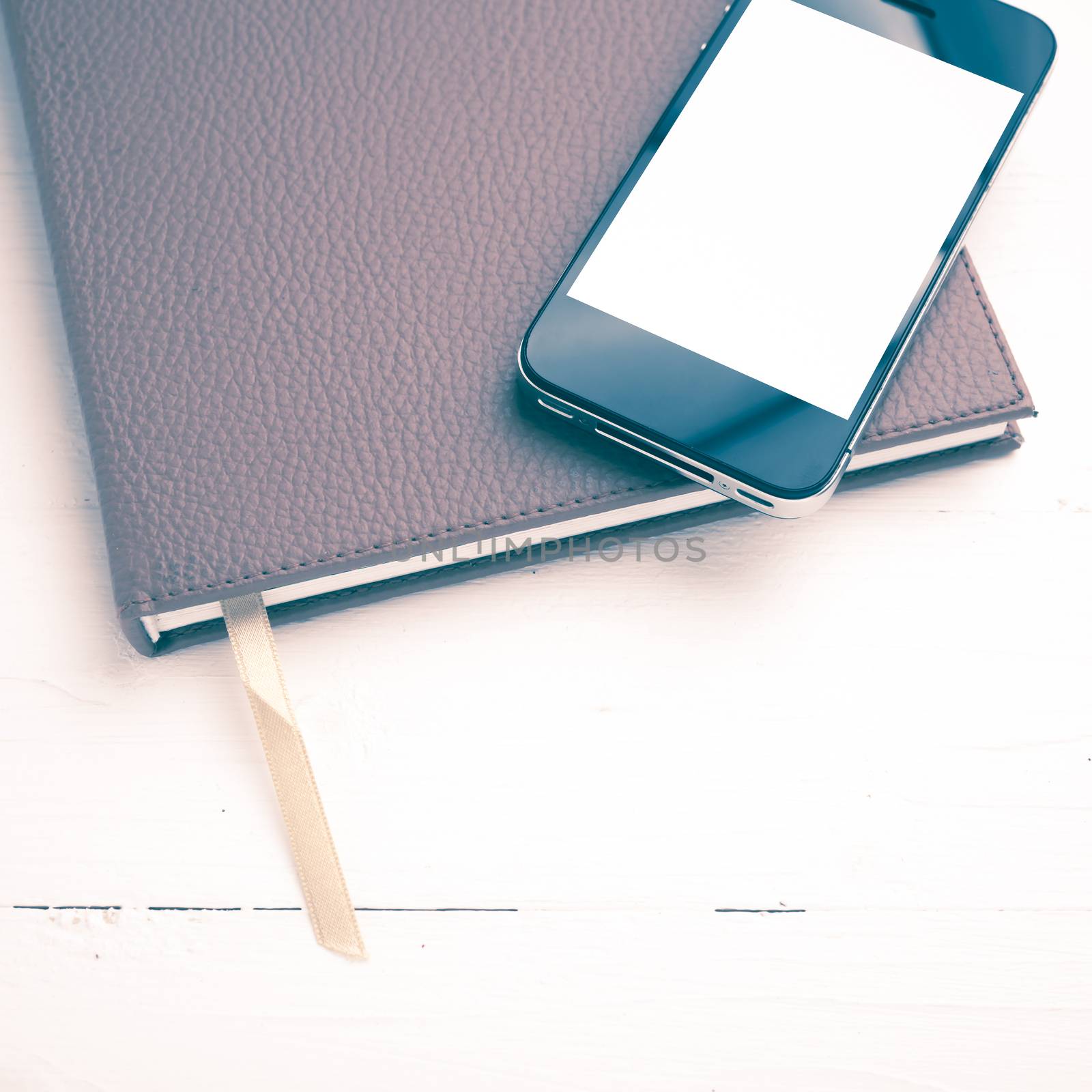 cellphone on notebook over white table vintage style