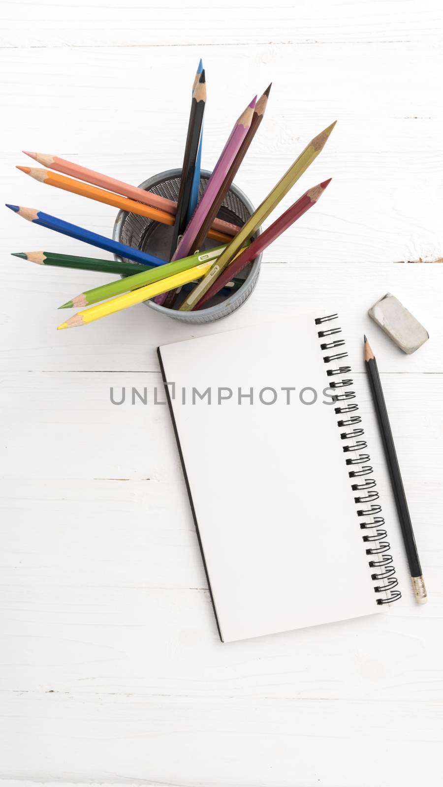 notepad with color pencil on white table view from above