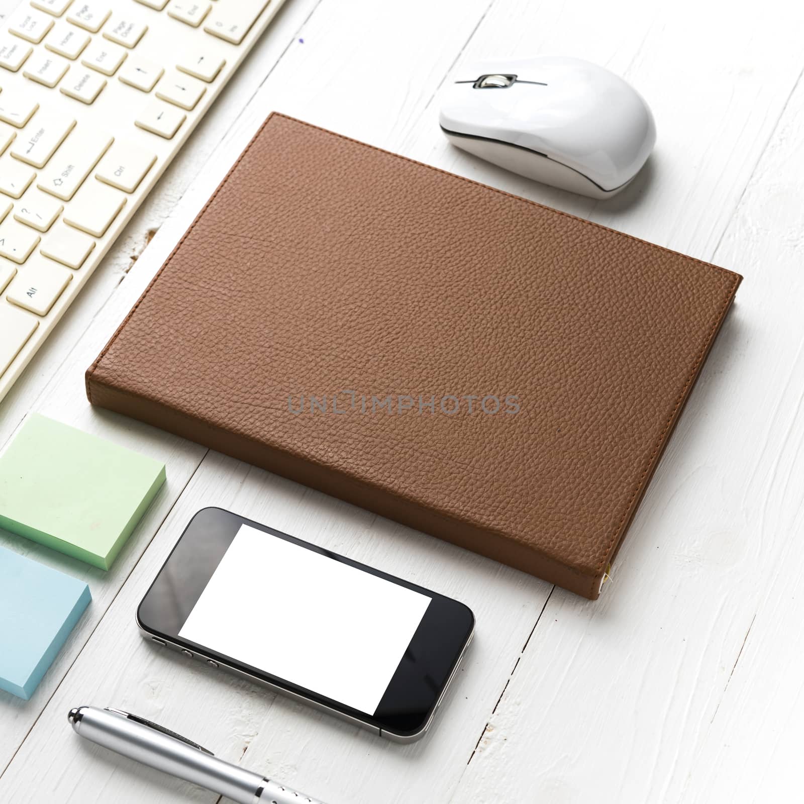 computer and brown notebook with office supplies on white table