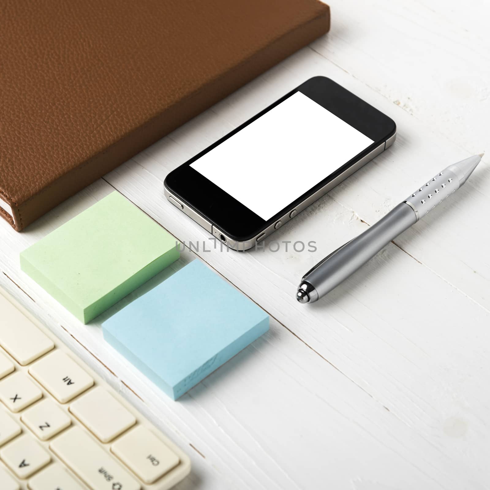 computer and brown notebook with office supplies on white table