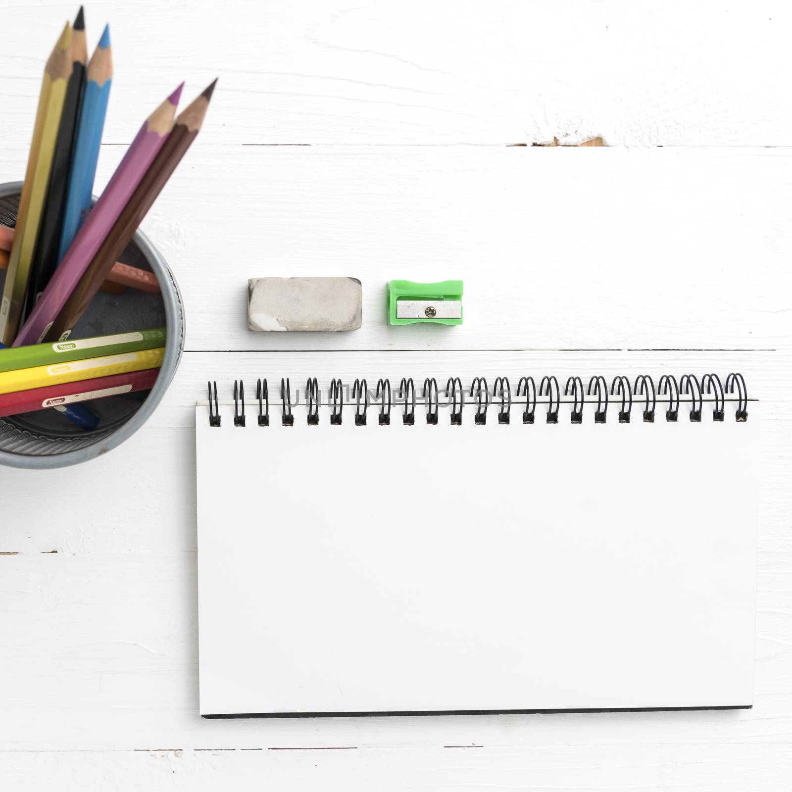 notepad with color pencil on white table view from above