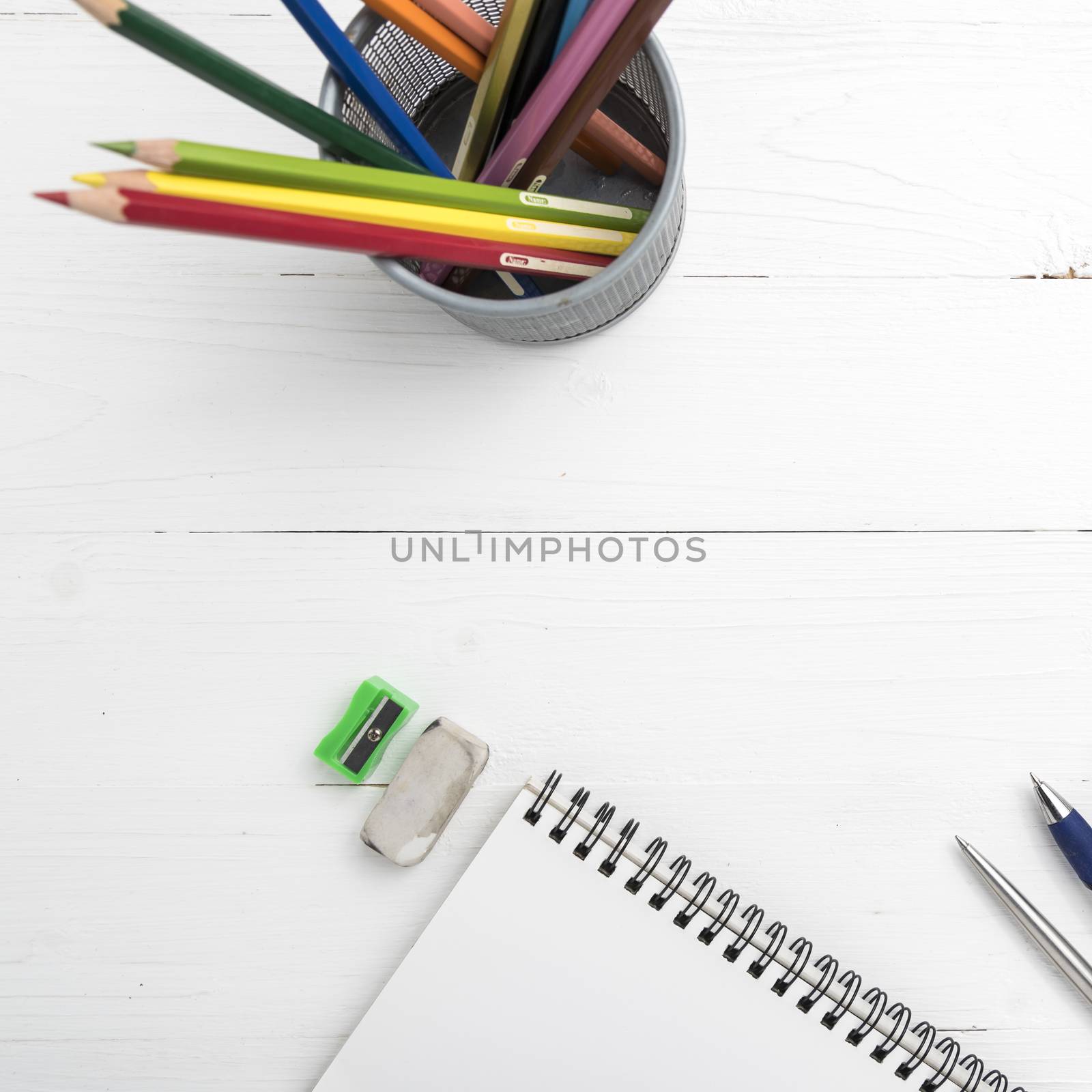 notepad with color pencil on white table view from above