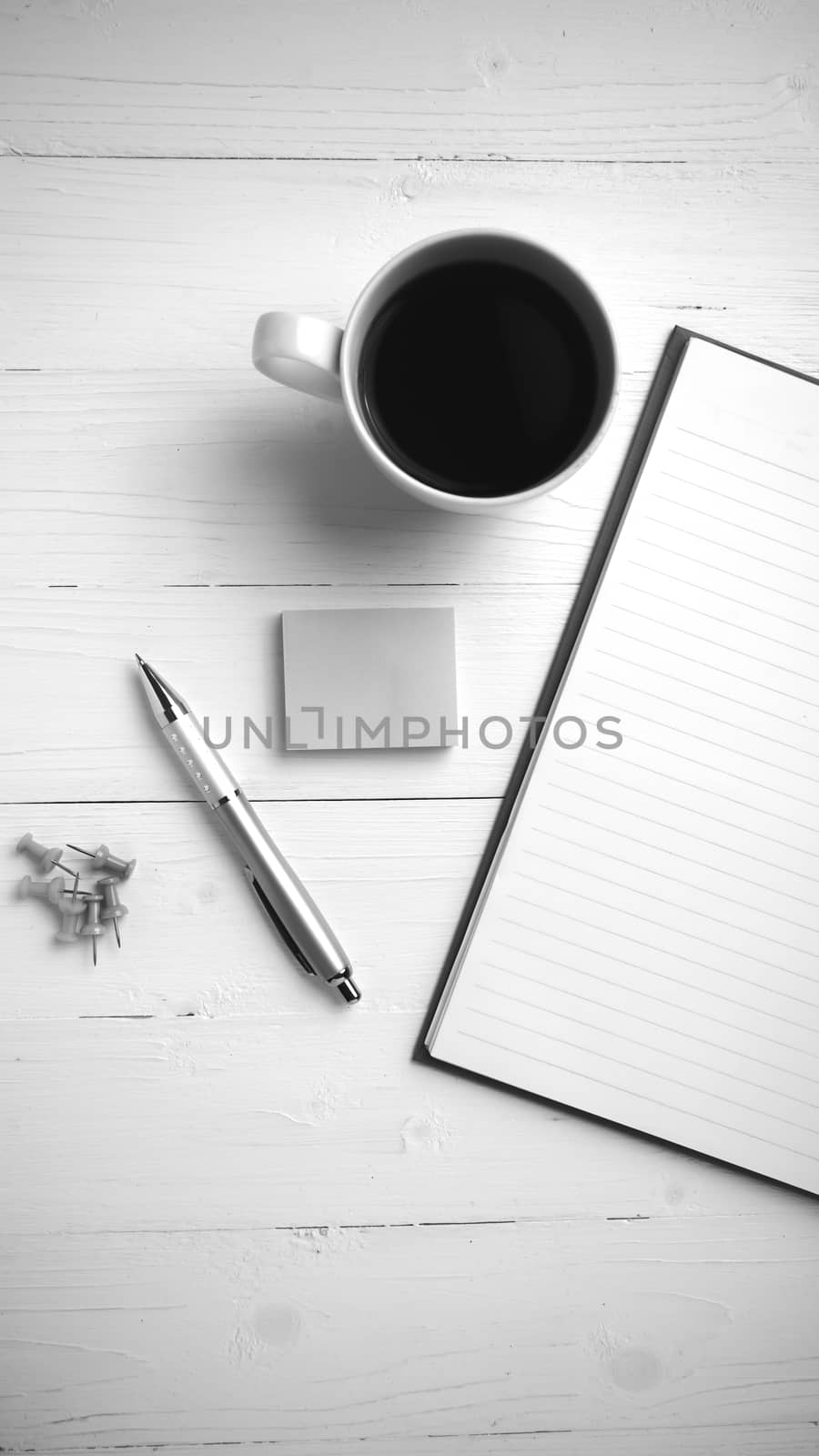 notepad and coffee cup on white table view from above black and white tone color style