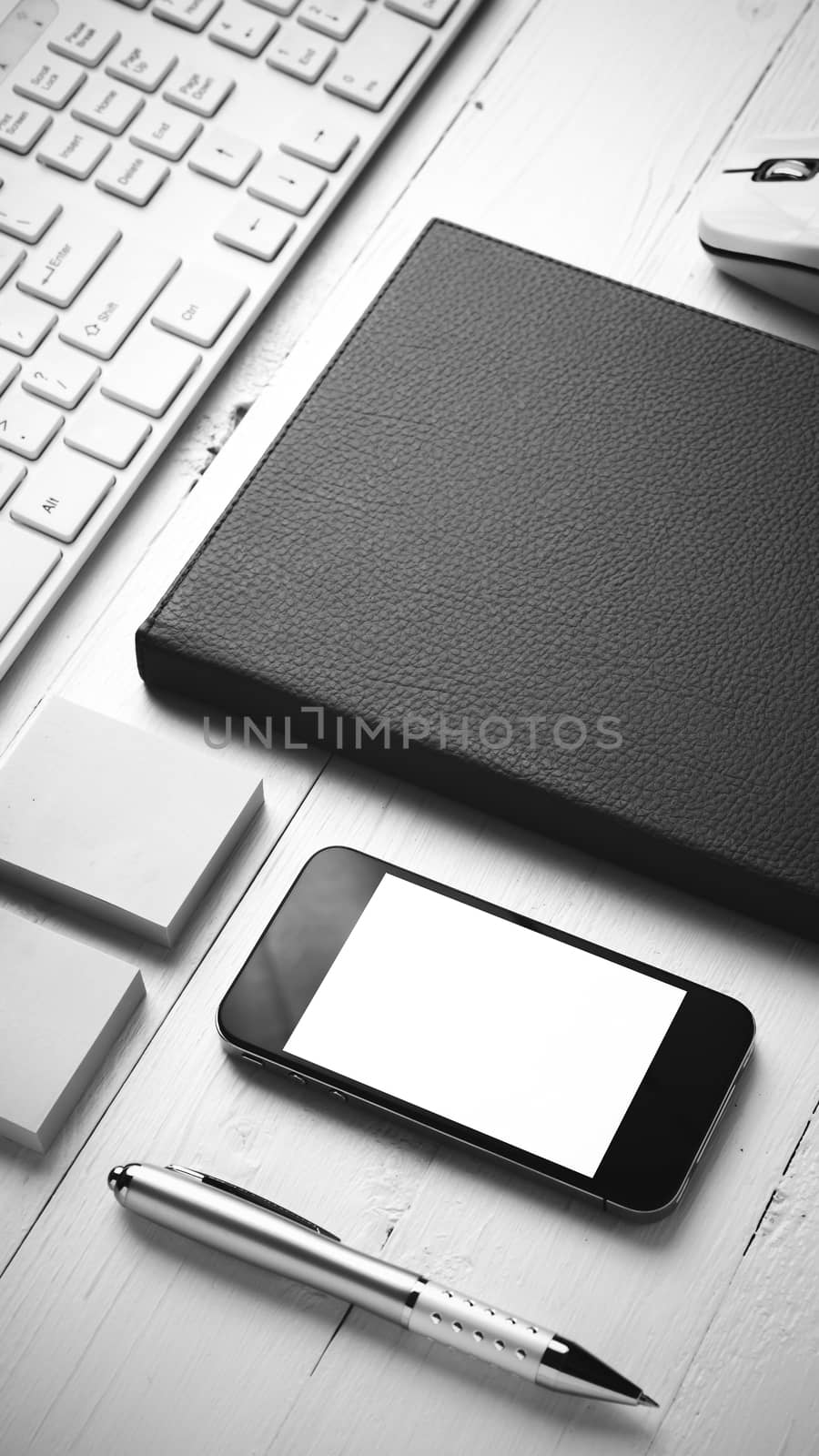 computer and brown notebook with office supplies on white table black and white style