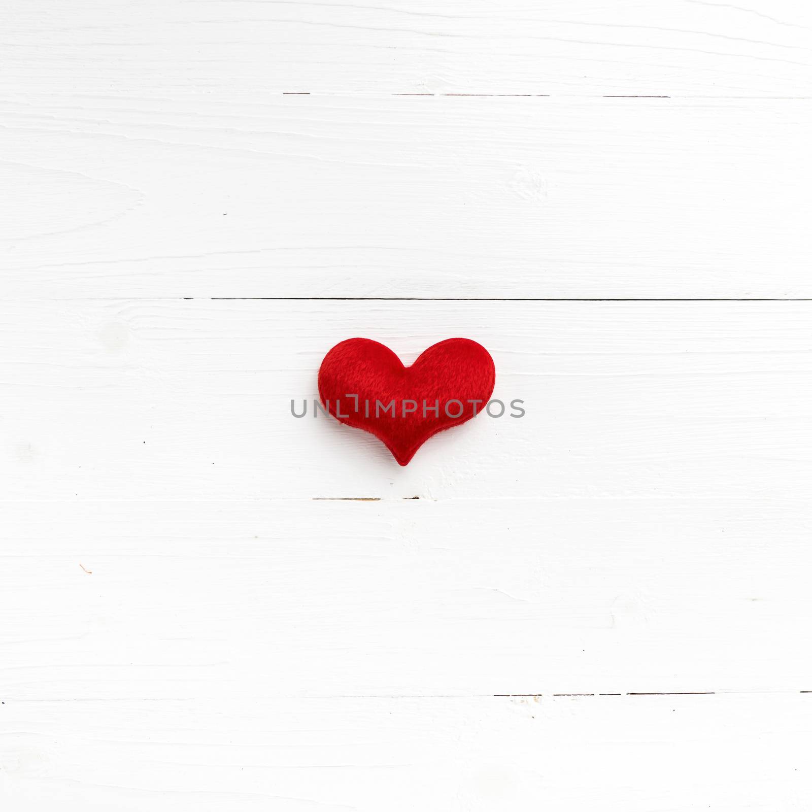 red heart on white table view from above