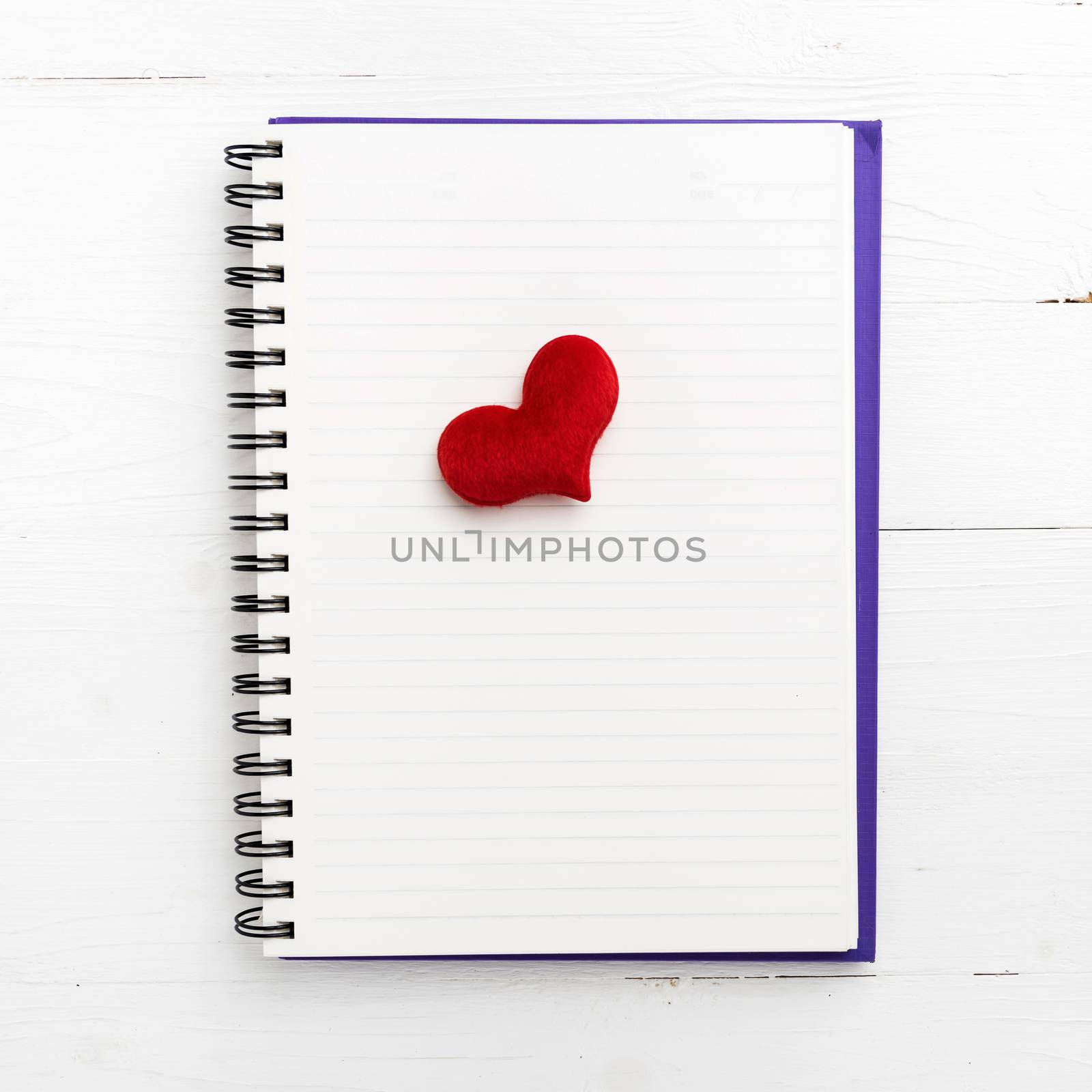 red heart on notepad on white table
