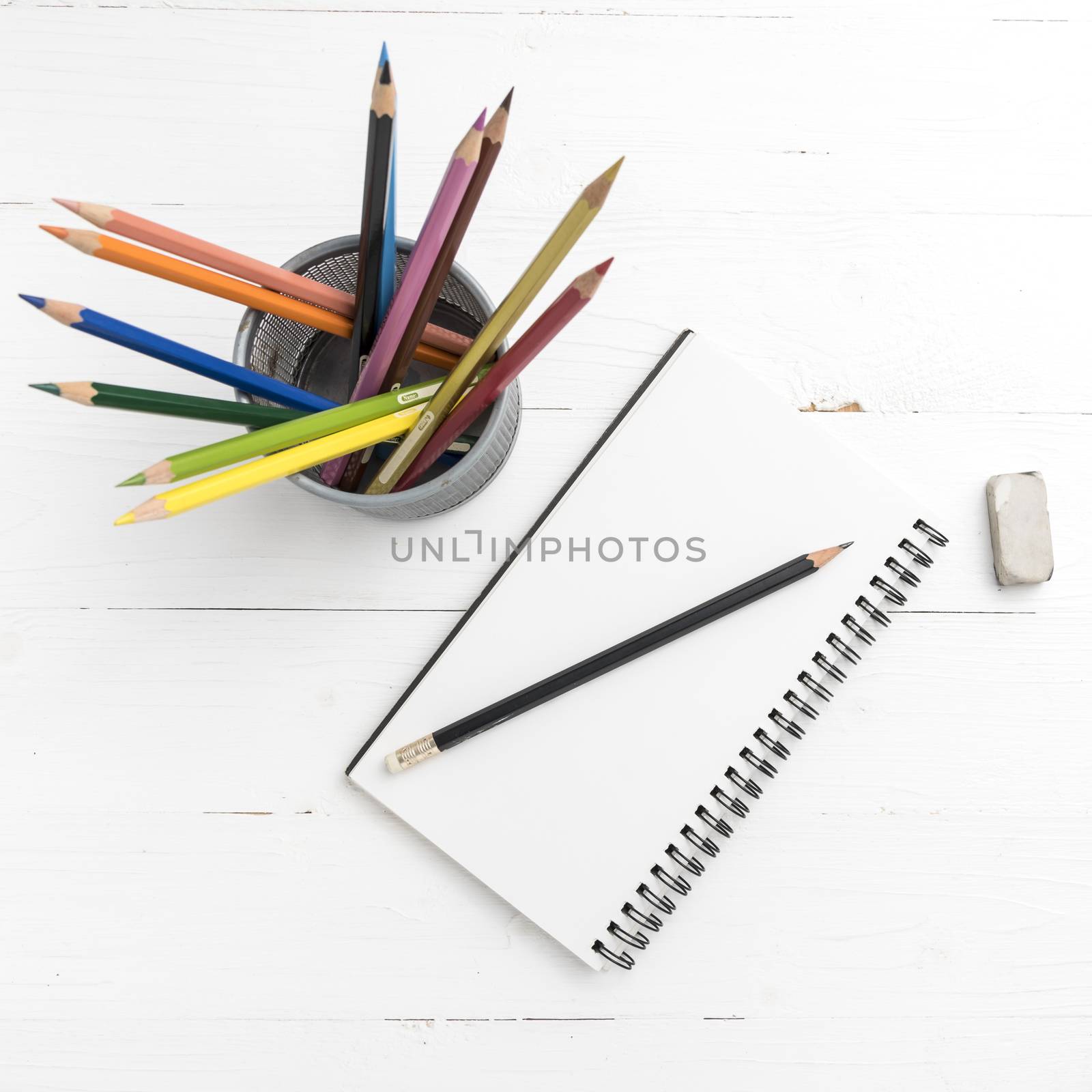 notepad with color pencil on white table view from above