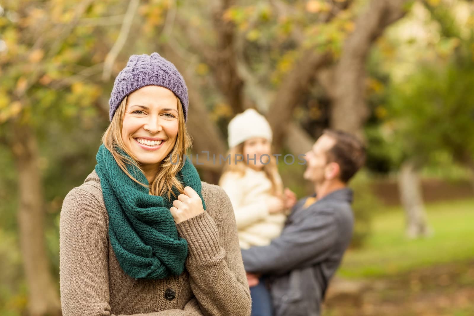 Smiling woman against her husband and her daughter on an autumns day