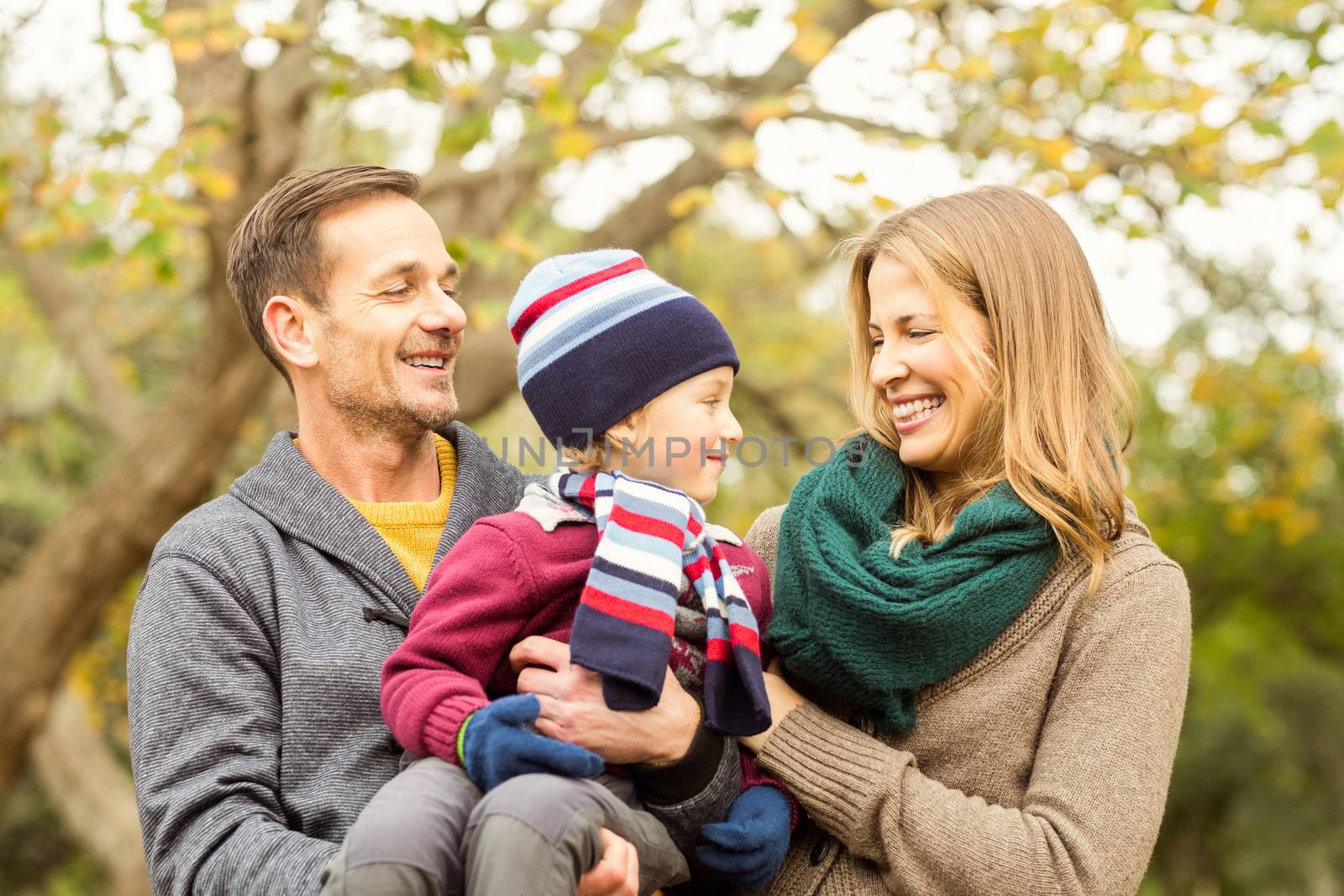 Smiling young couple with small boy posing on an autumns day