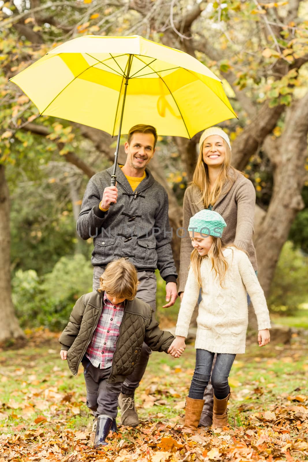 Smiling young family under umbrella on an autumns day