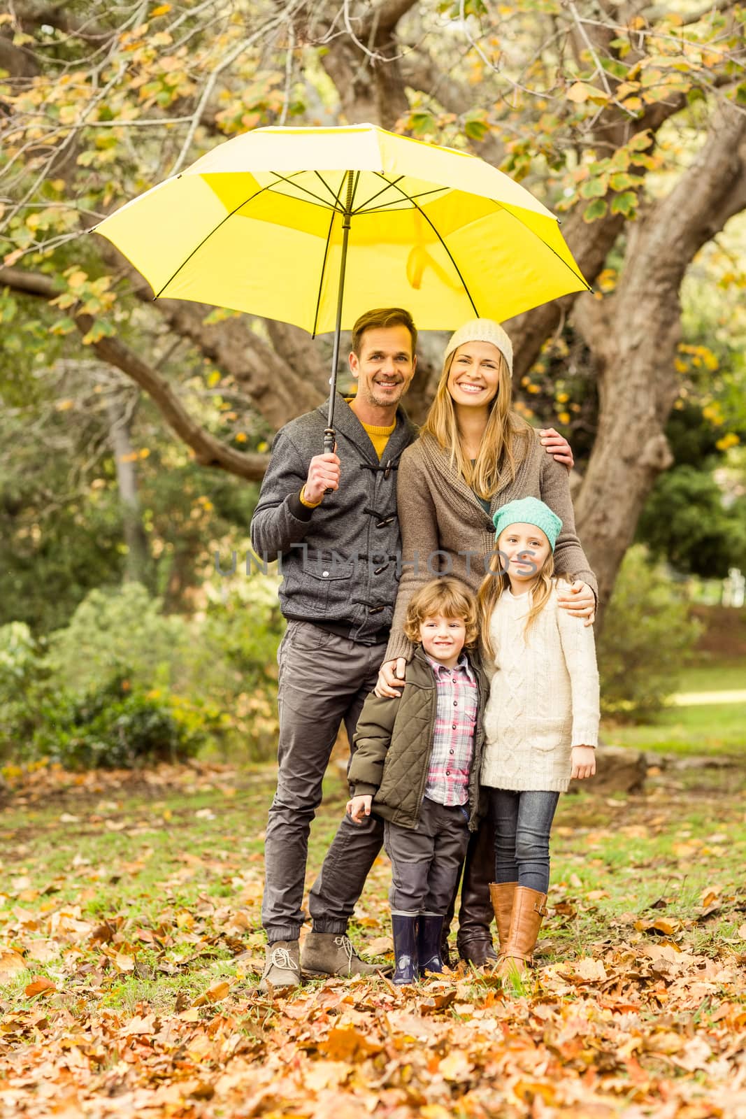 Smiling young family under umbrella by Wavebreakmedia
