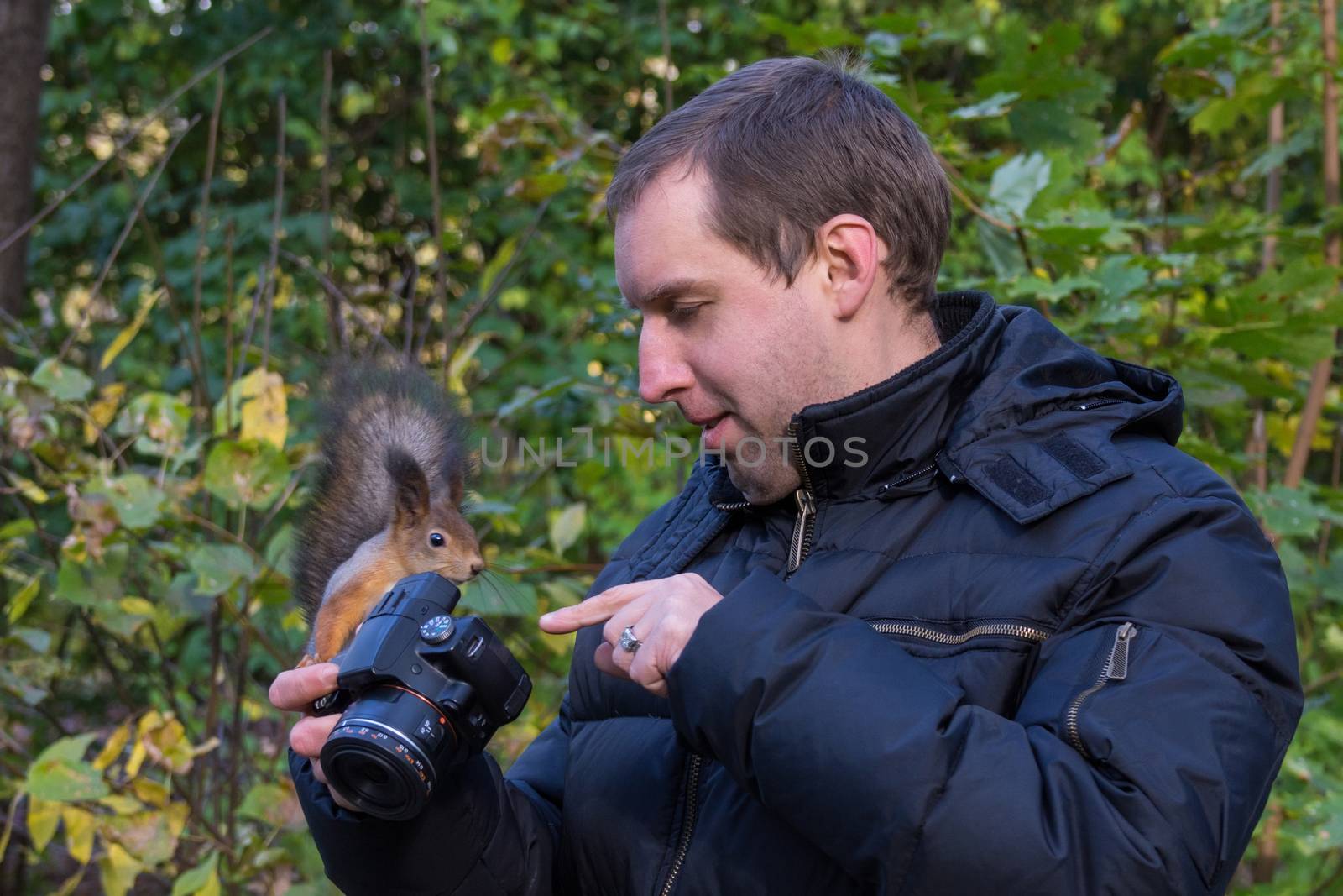 The photograph depicts a male photographer with a squirrel