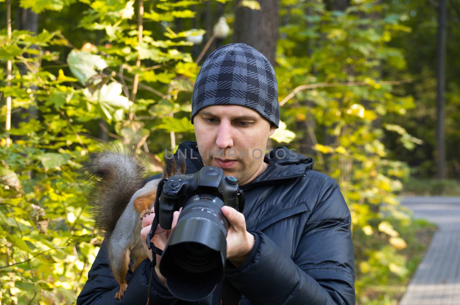 The photograph depicts a male photographer with a squirrel