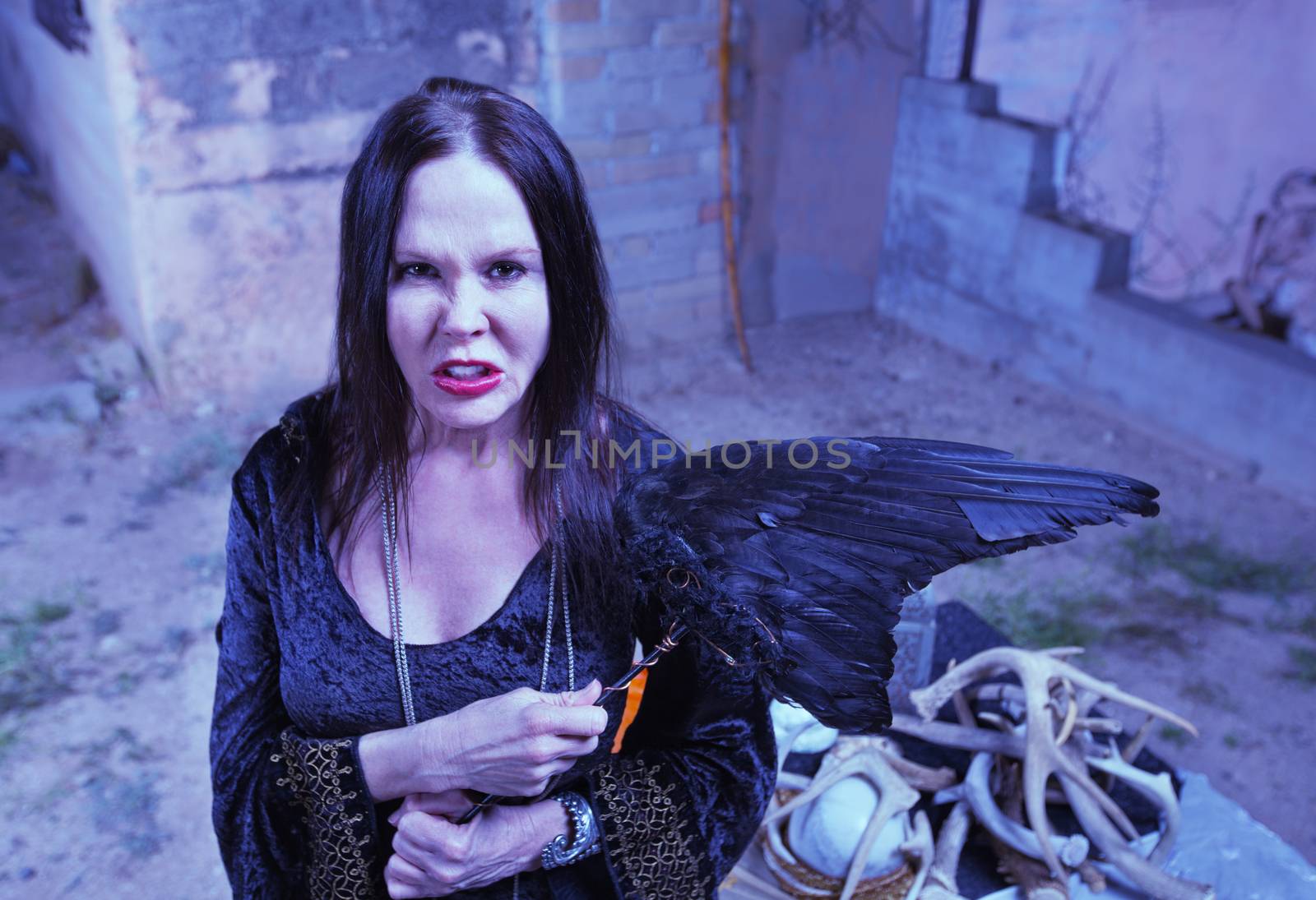 Scary female witch with fetish object near altar
