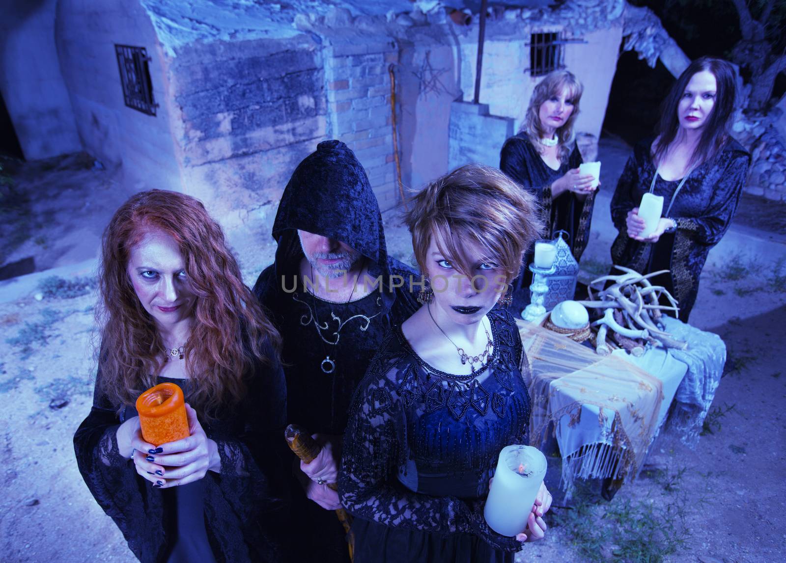 Coven of five witches outdoors holding candles