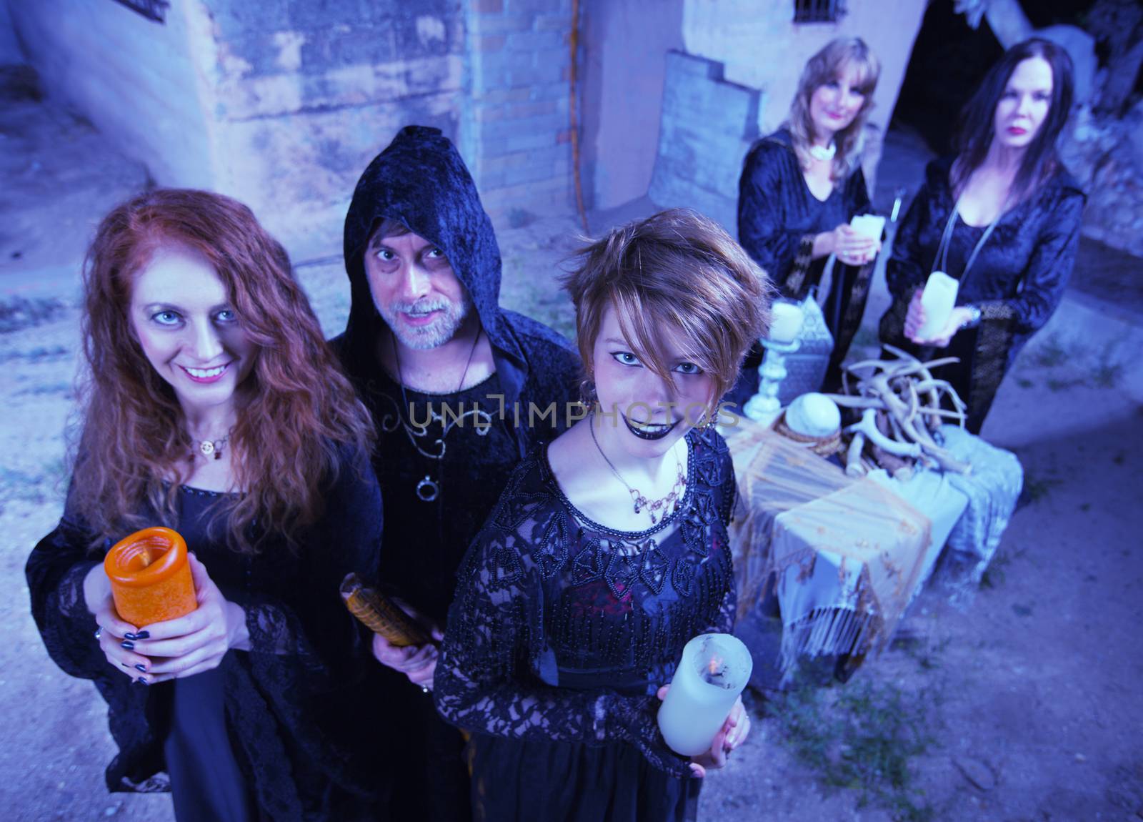 Coven of smiling witches outdoors holding candles