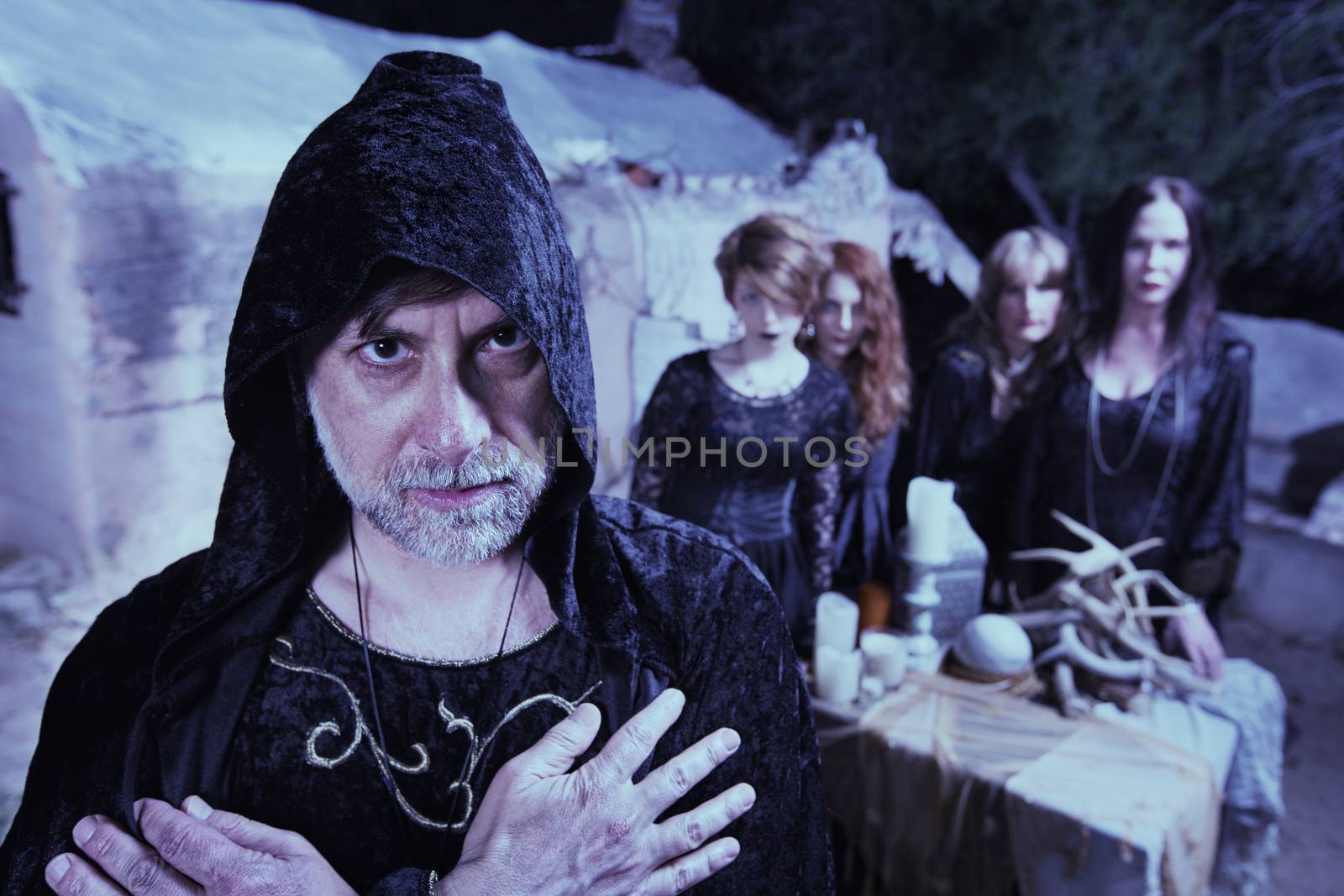 Occult man in hood with group of women at temple