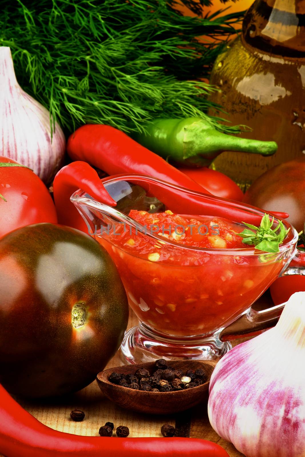 Bruschetta Sauce in Glass Gravy Boat with Black Tomatoes, Garlic, Chili Peppers, Dill and Olive Oil in Glass Bottle closeup