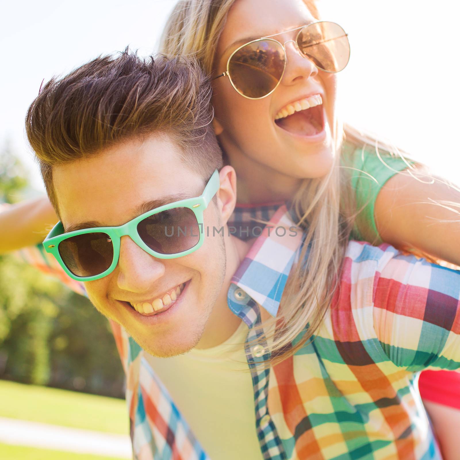 holidays, vacation, love and friendship concept - smiling teen couple in sunglasses having fun in summer park