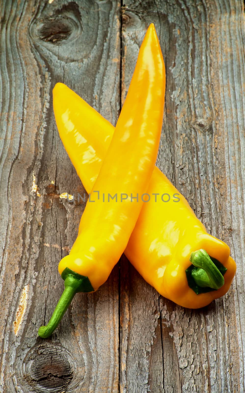 Arrangement of Perfect Ripe Yellow Ramiro Peppers with Green Tails isolated on Rustic Wooden background