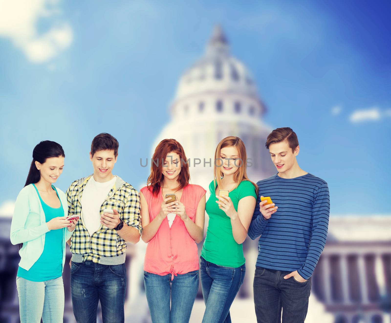 smiling students with smartphones by dolgachov