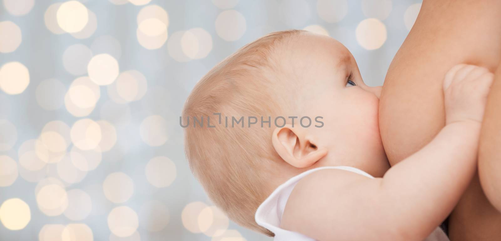 motherhood, children, people and care concept - close up of mother breast feeding adorable baby over holidays lights background