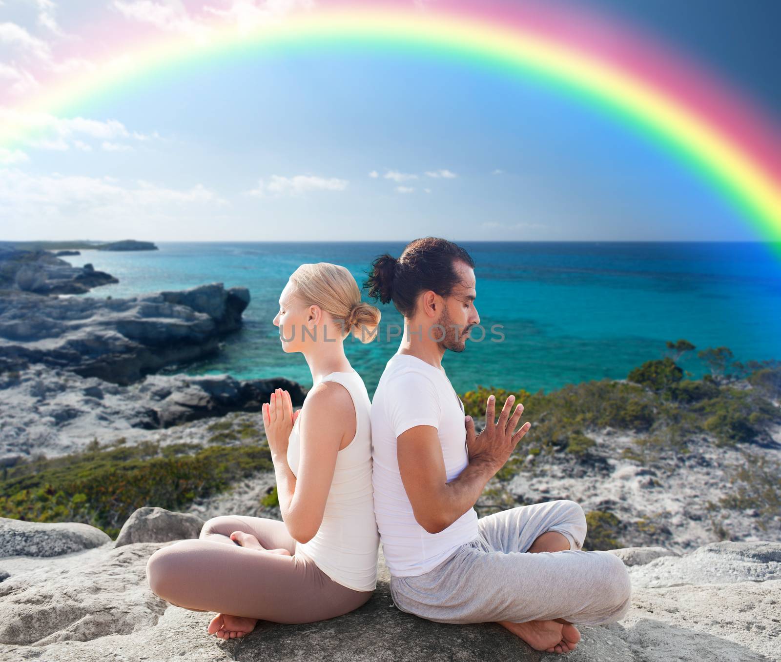 happy couple meditating in lotus pose on beach by dolgachov