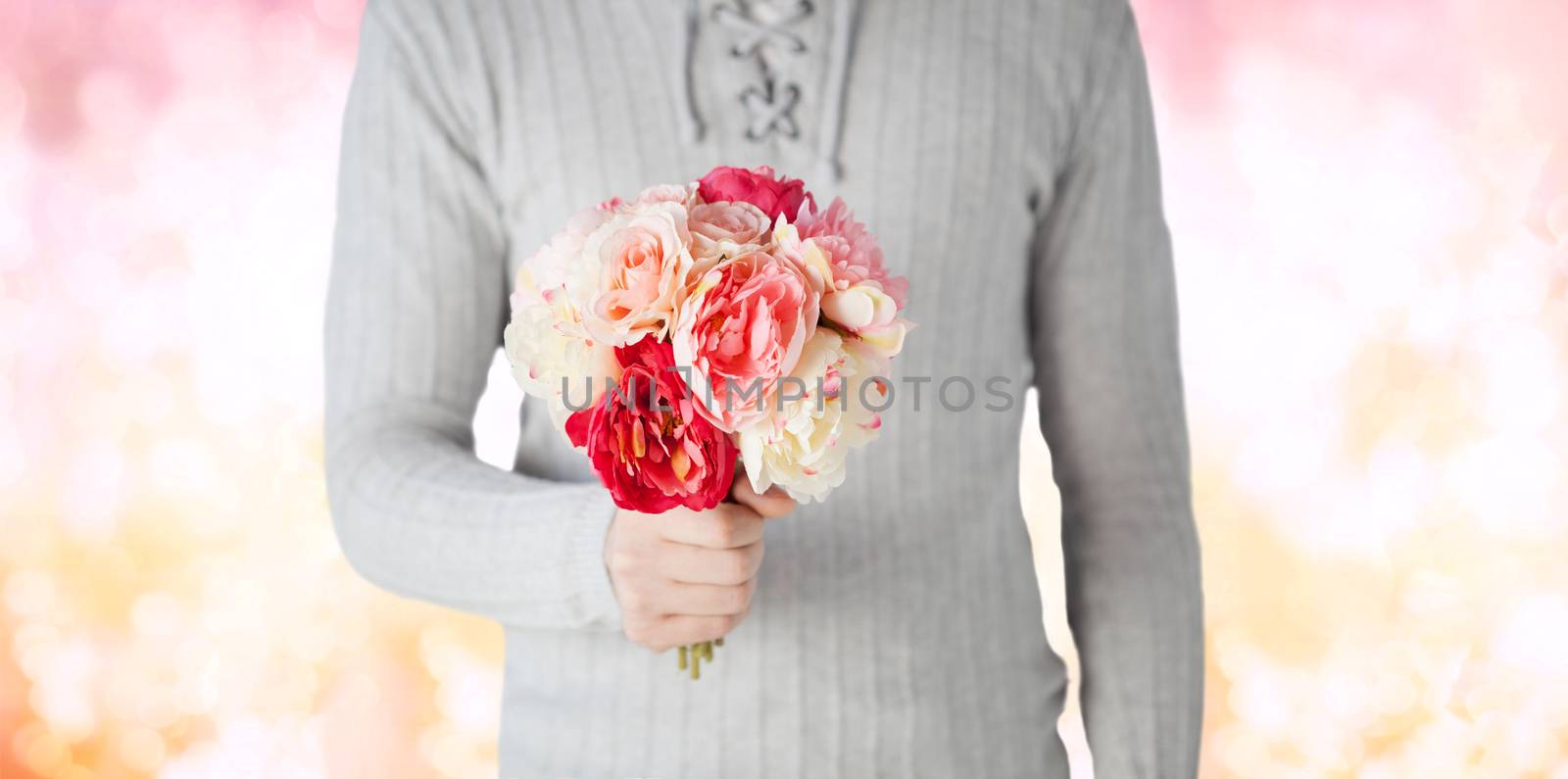 holidays, people, feelings and greetings concept - close up of man holding bunch of flowers over pink lights background