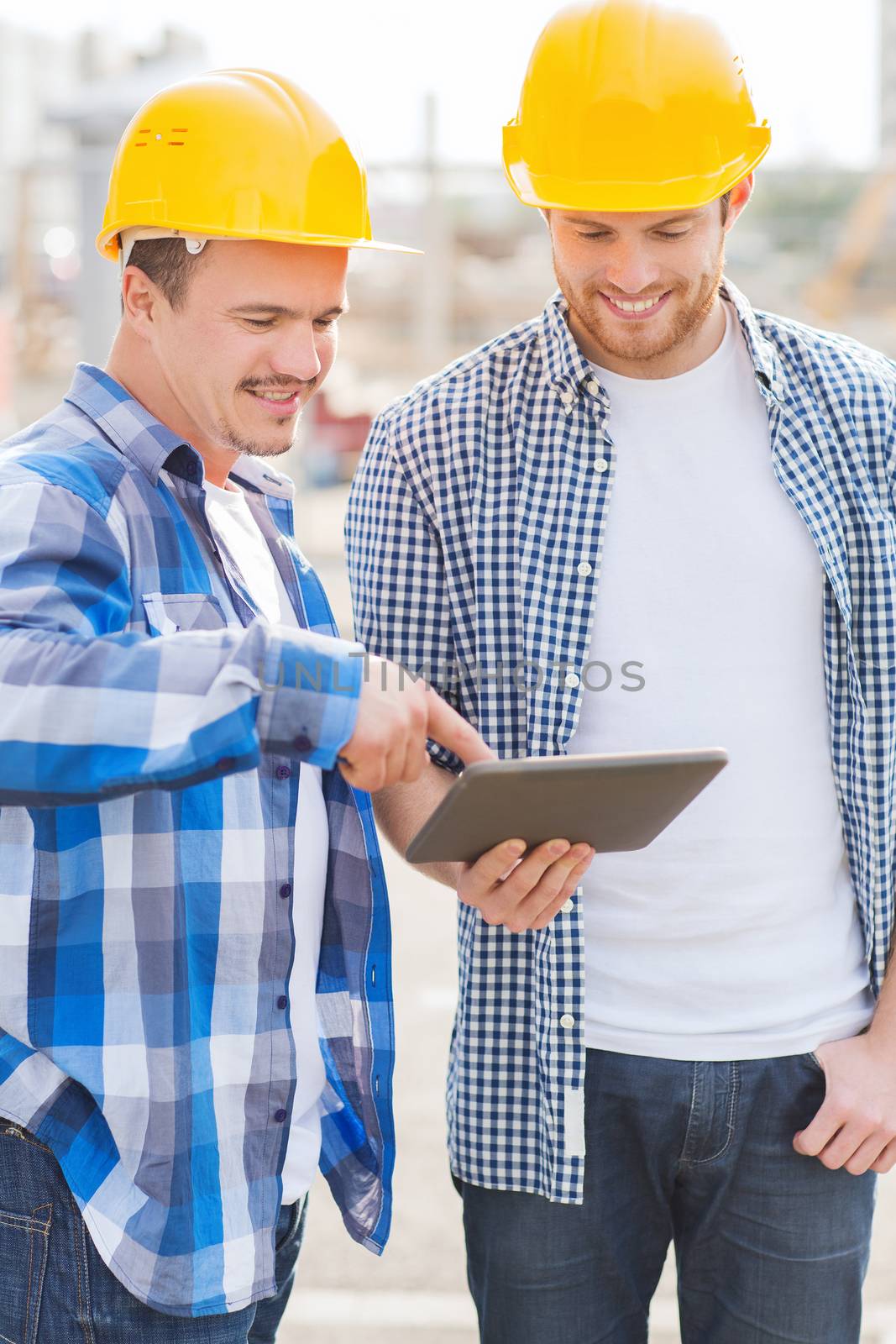 business, building, teamwork, technology and people concept - group of smiling builders in hardhats with tablet pc computer outdoors