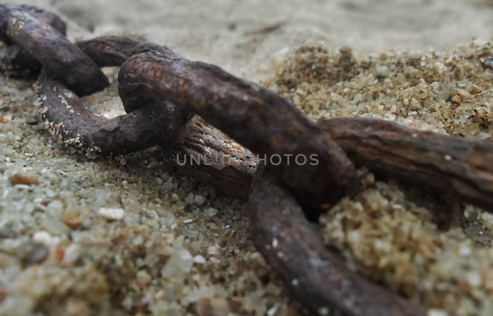 a close up of a decaying rusted chain on beach sand