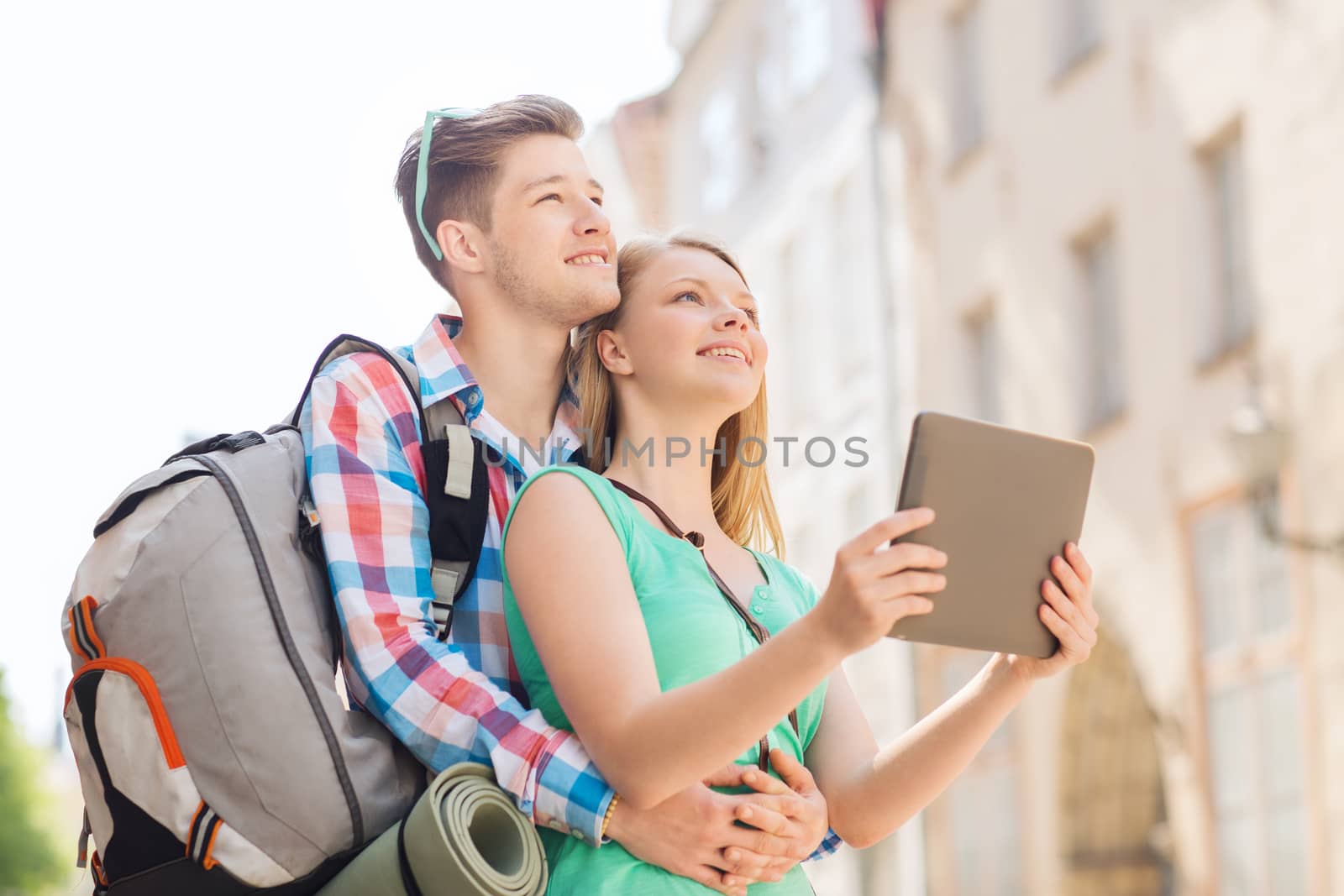 travel, vacation, technology and friendship concept - smiling couple with tablet pc and backpack in city
