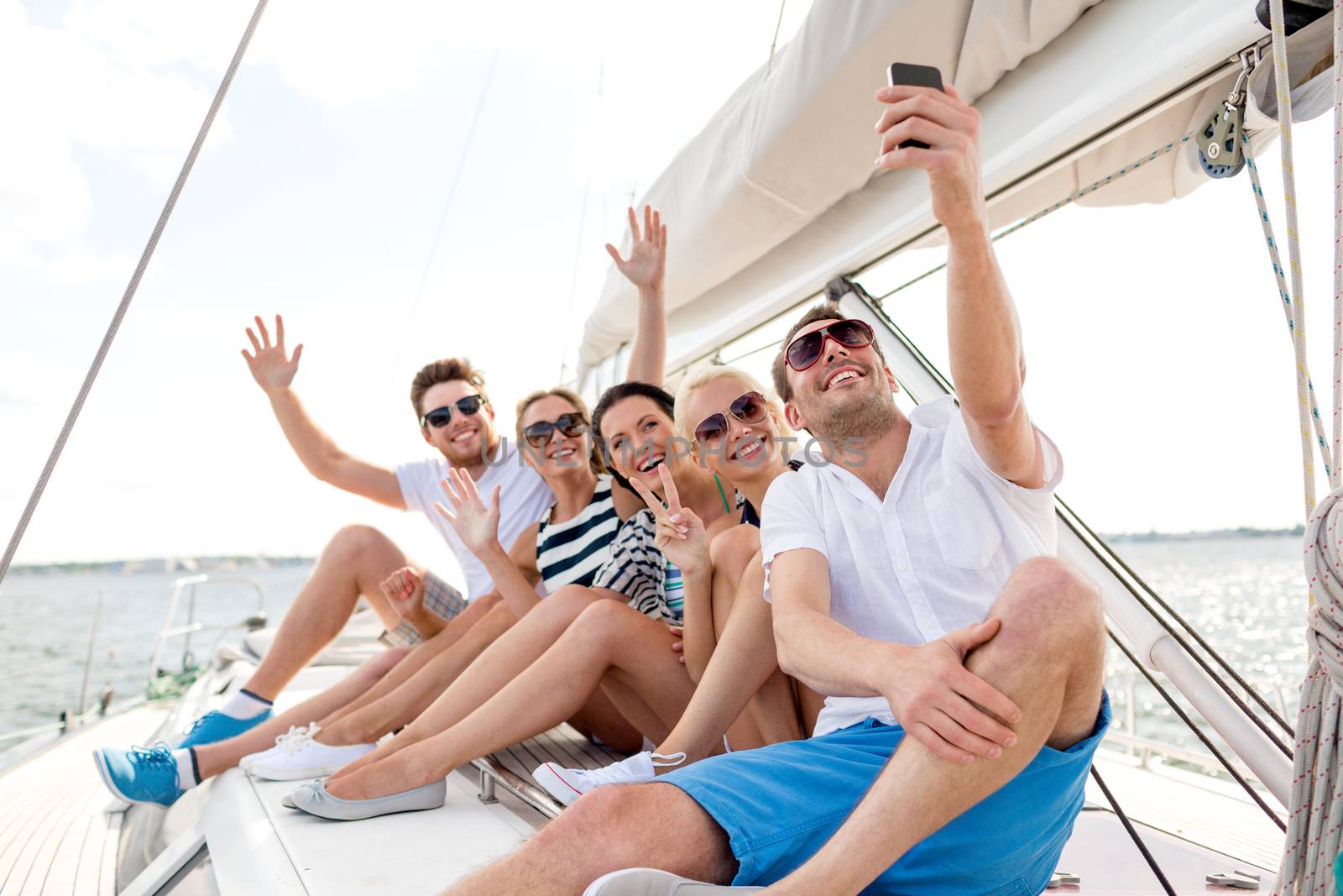 smiling friends sitting on yacht deck by dolgachov