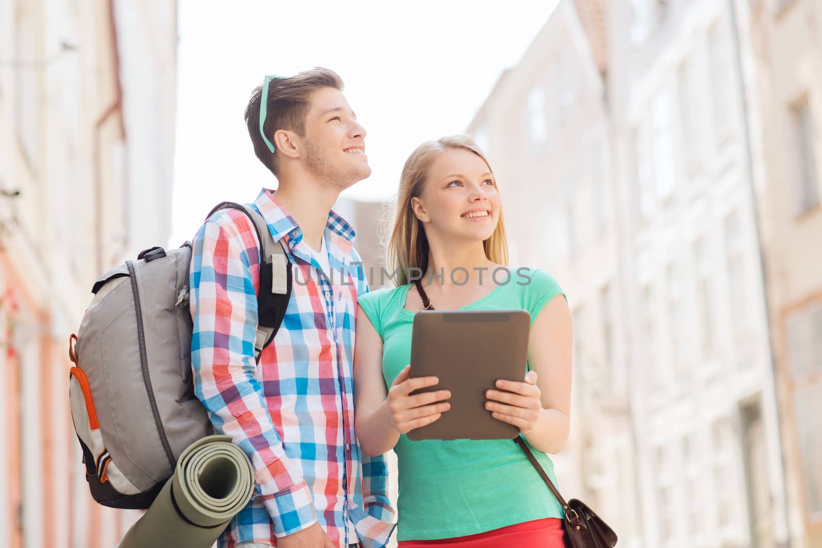 travel, vacation, technology and friendship concept - smiling couple with tablet pc and backpack in city