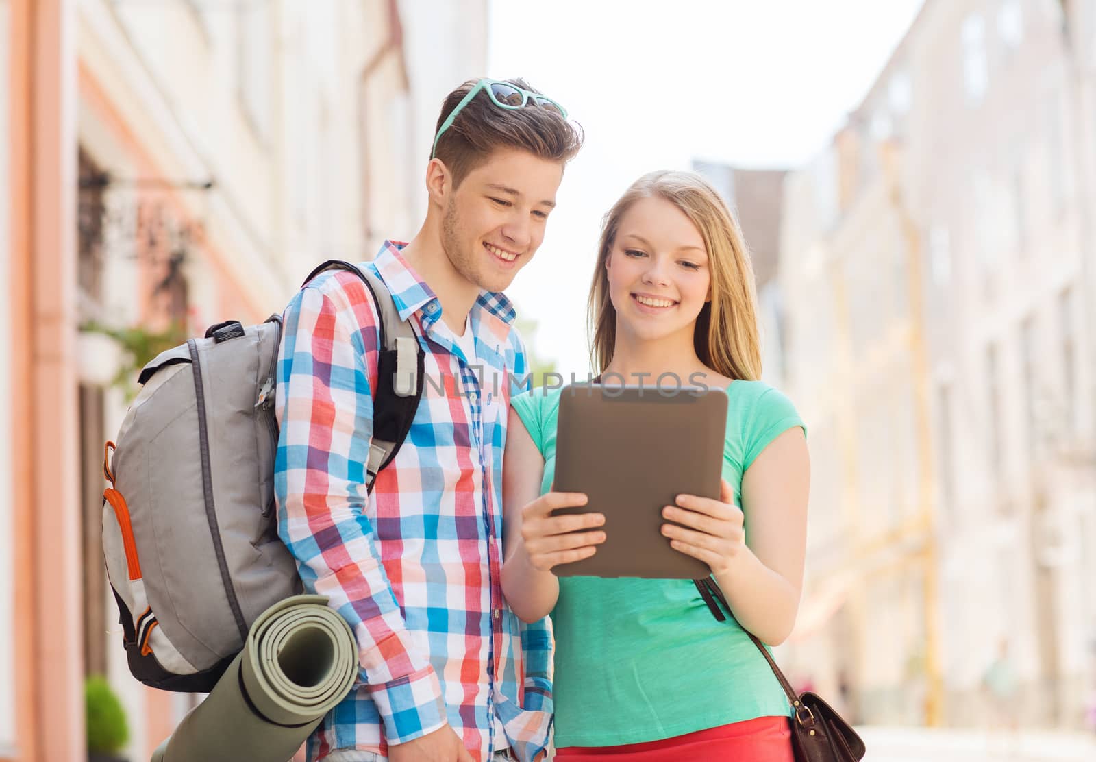 travel, vacation, technology and friendship concept - smiling couple with tablet pc and backpack in city