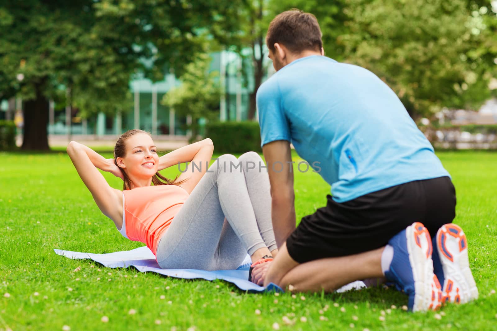 smiling woman doing exercises on mat outdoors by dolgachov