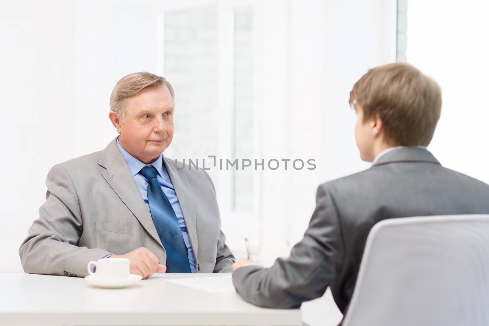 older man and young man signing papers in office by dolgachov