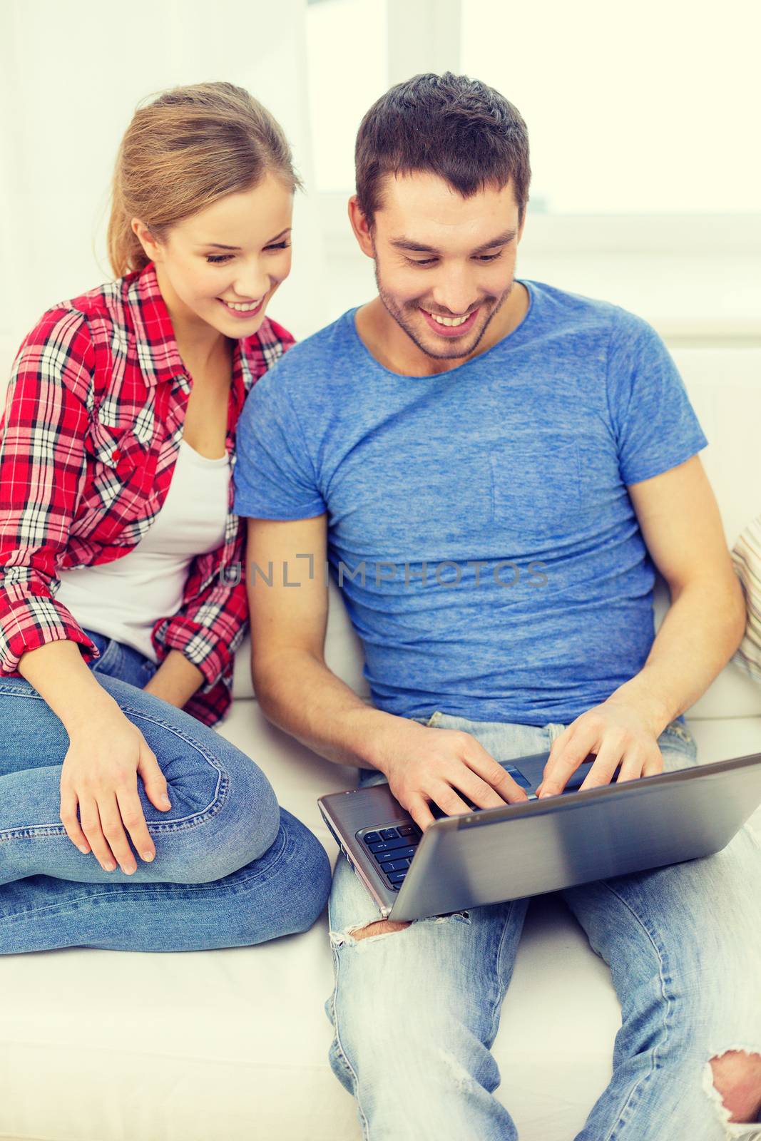 home, technology and relationships concept - smiling couple with laptop computer at home