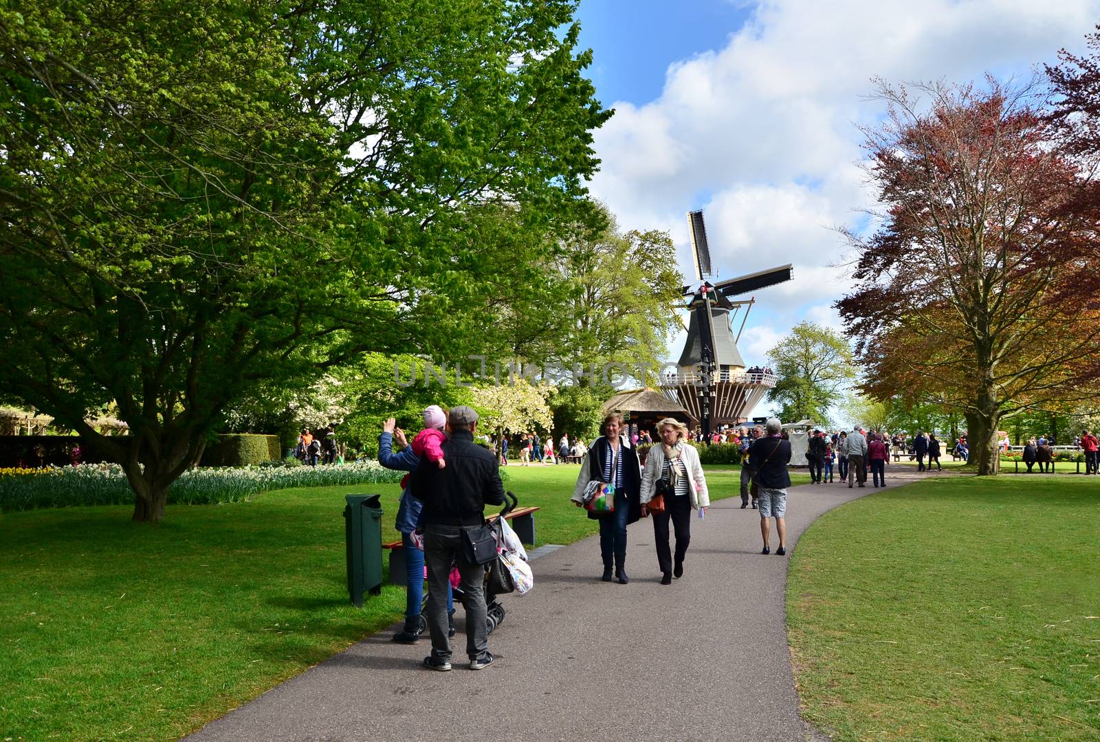 Lisse, The Netherlands - May 7, 2015: Old windmill with many tourists in famous garden in Keukenhof. Keukenhof is the most beautiful spring garden in the world.