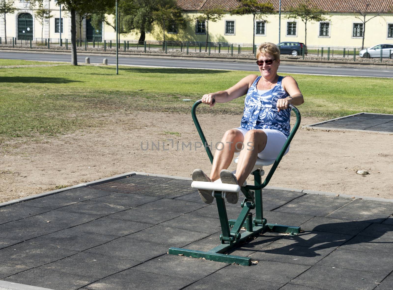 adult woman with sunglaeese training on outside crosstrainer in the park in lisbon portugal