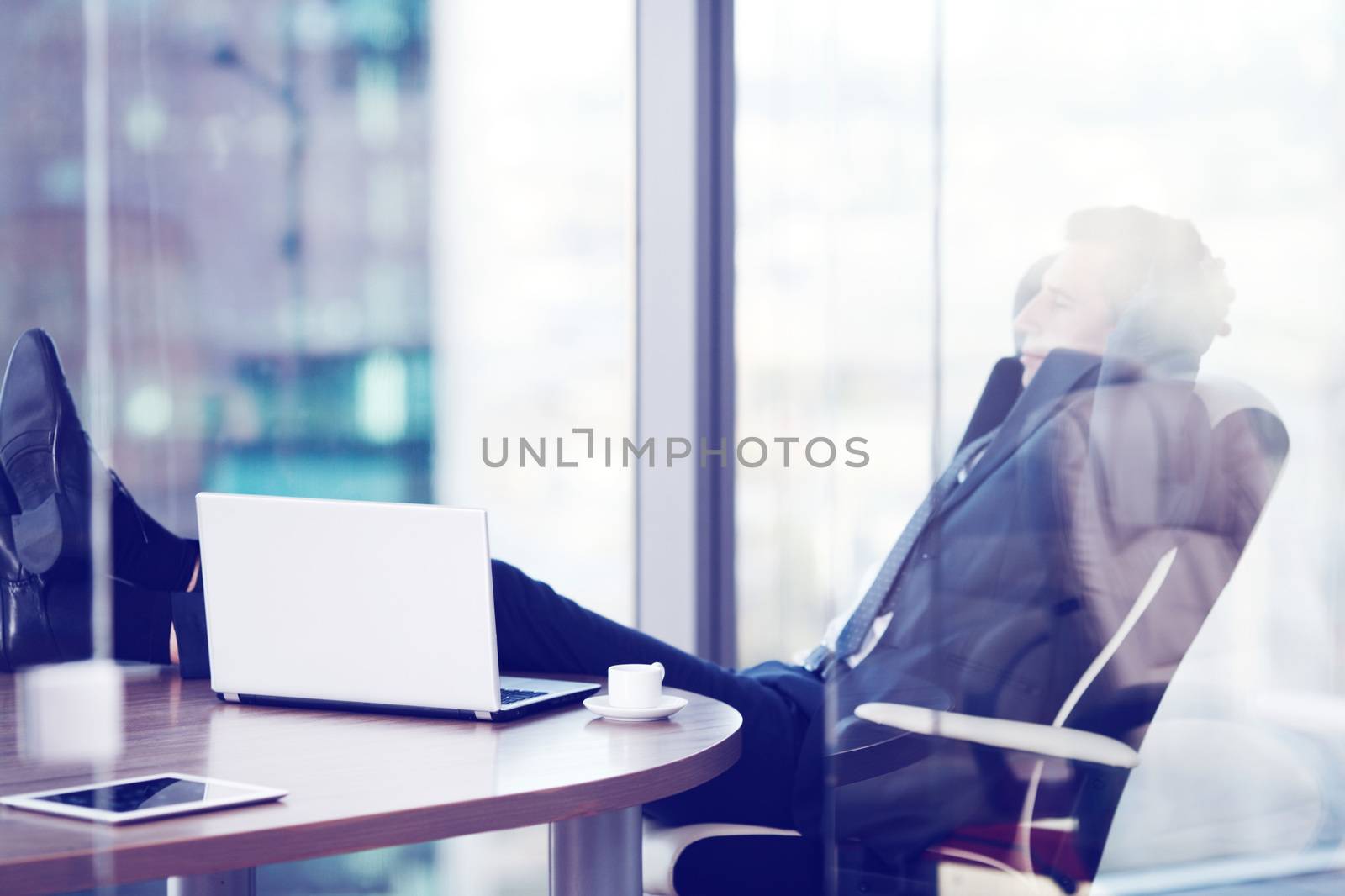 Businessman relaxes sitting in the office and looking in window