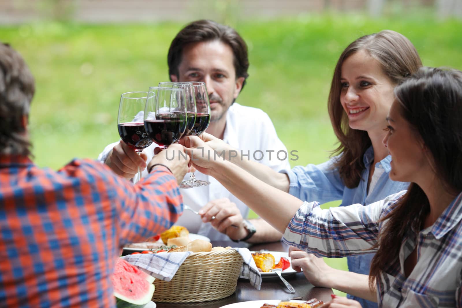 Friends clink glasses of red wine at outdoor dinner