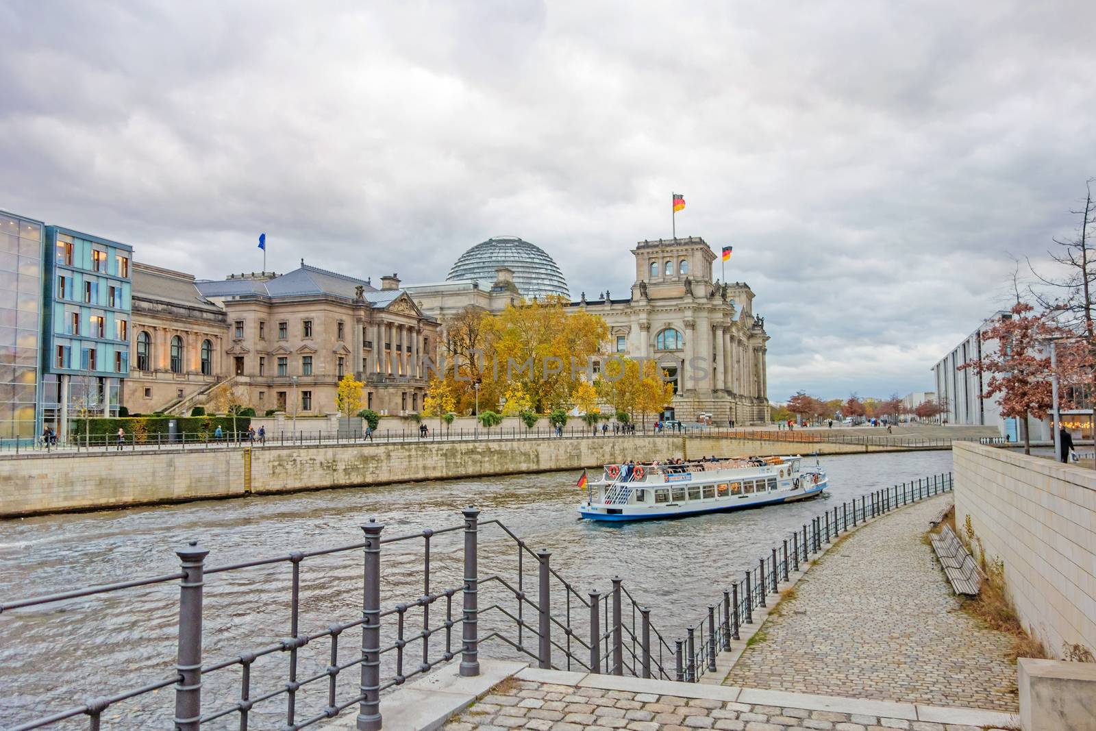 Berlin, Germany - October 28, 2013: Spree river with sightseeing passenger boat and Reichstag building in the background. Government district in Berlin-Mitte, where politic is made in Germany.