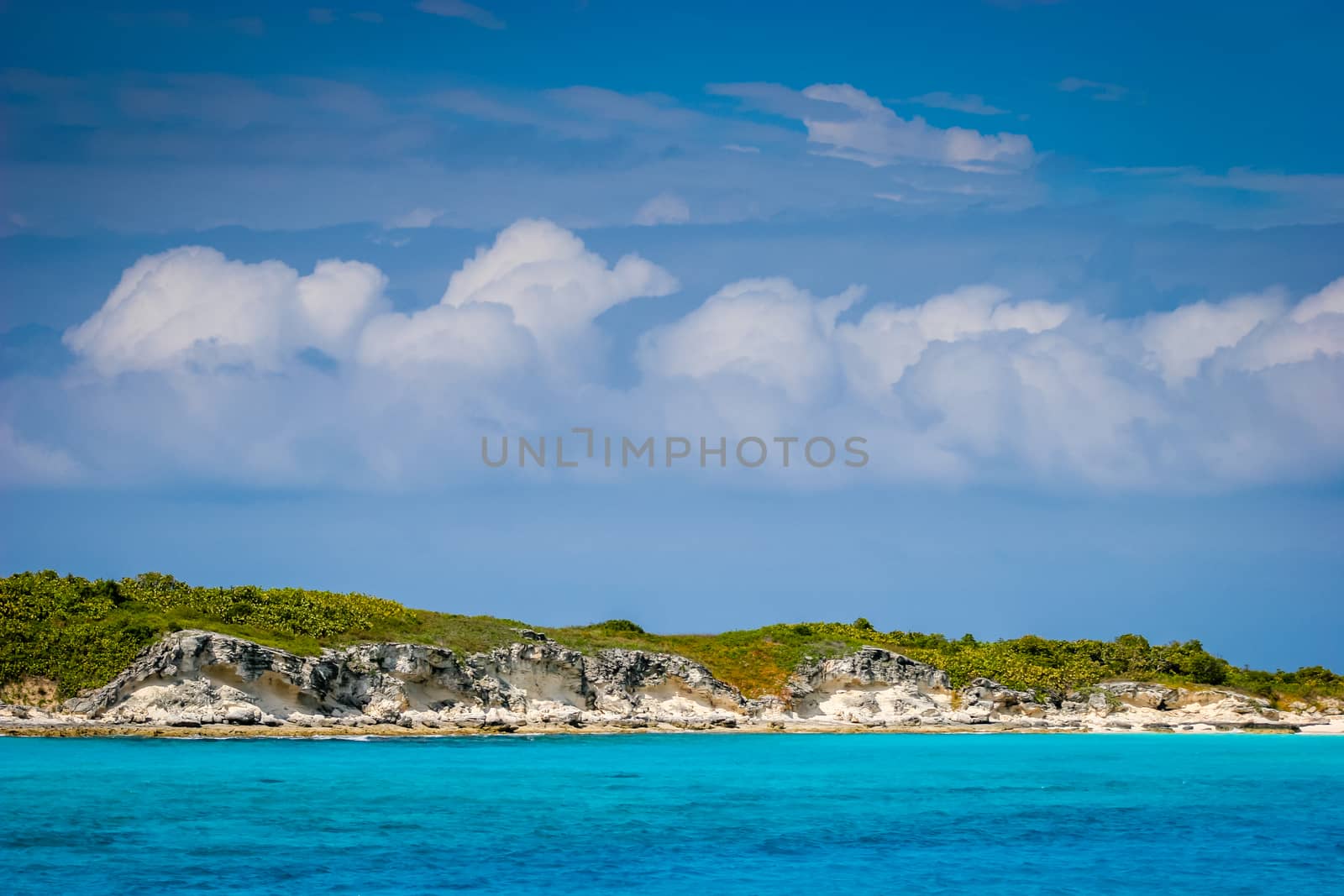 An isolated small Bahamian island separates the blue sky from the brilliant blue water.