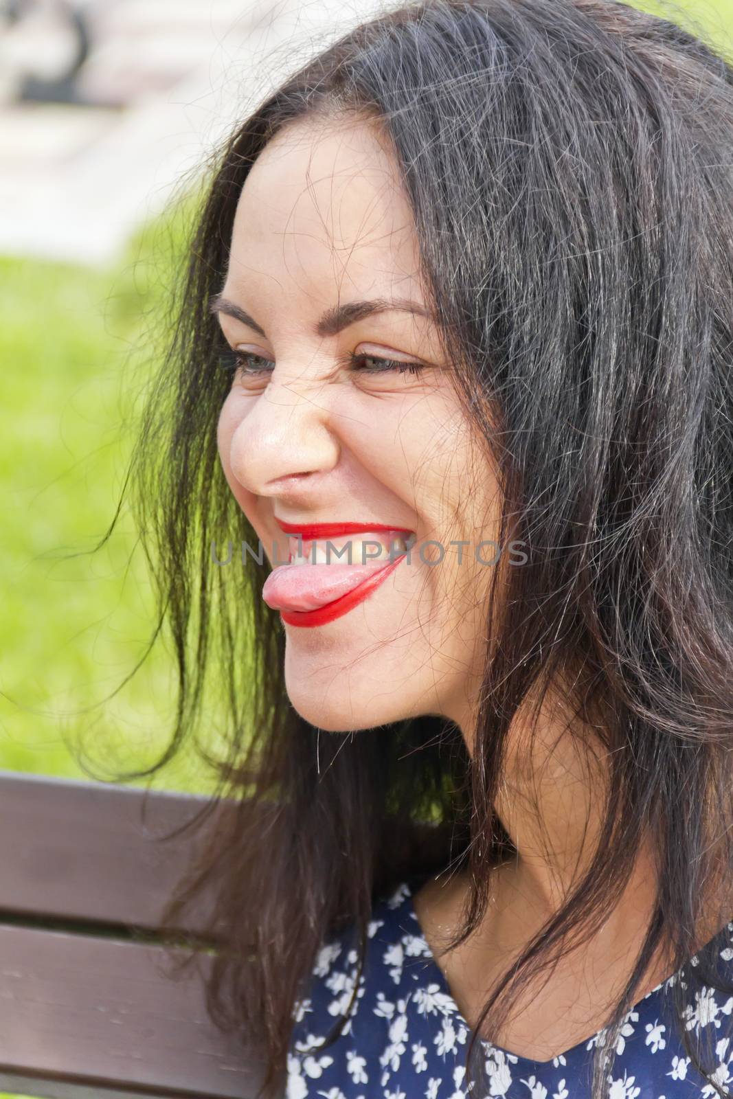 Portrait brunette with red lipstick and put out tongue