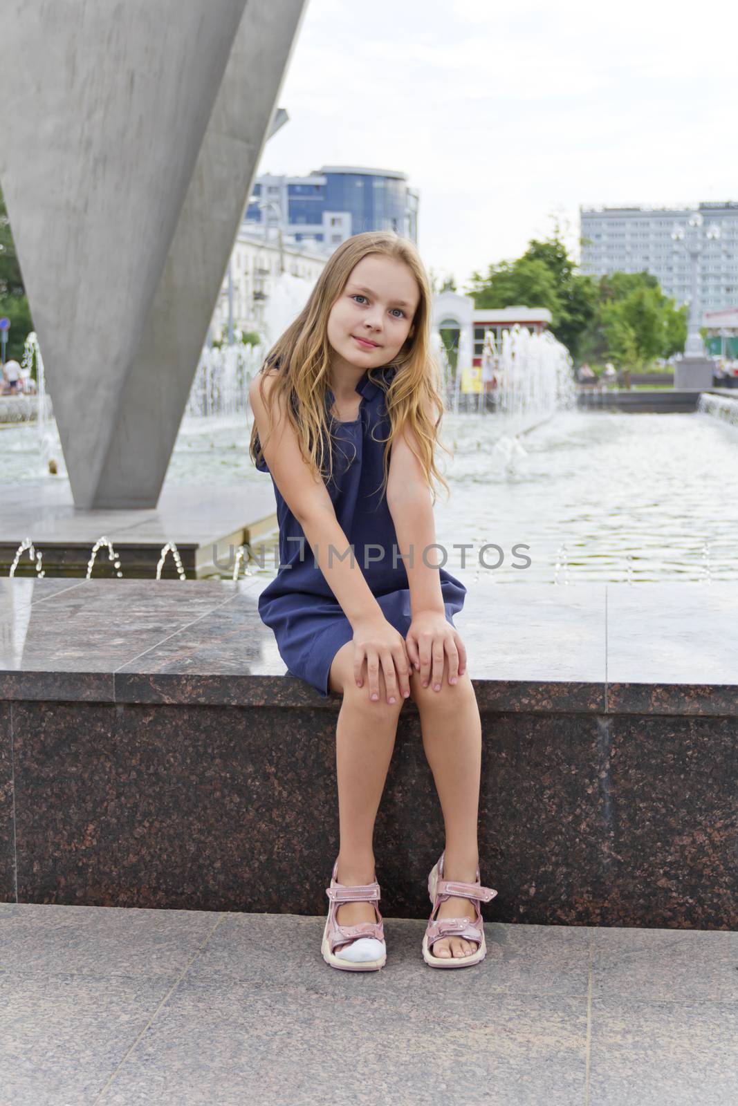 Cute girl with blond hair on fountain background